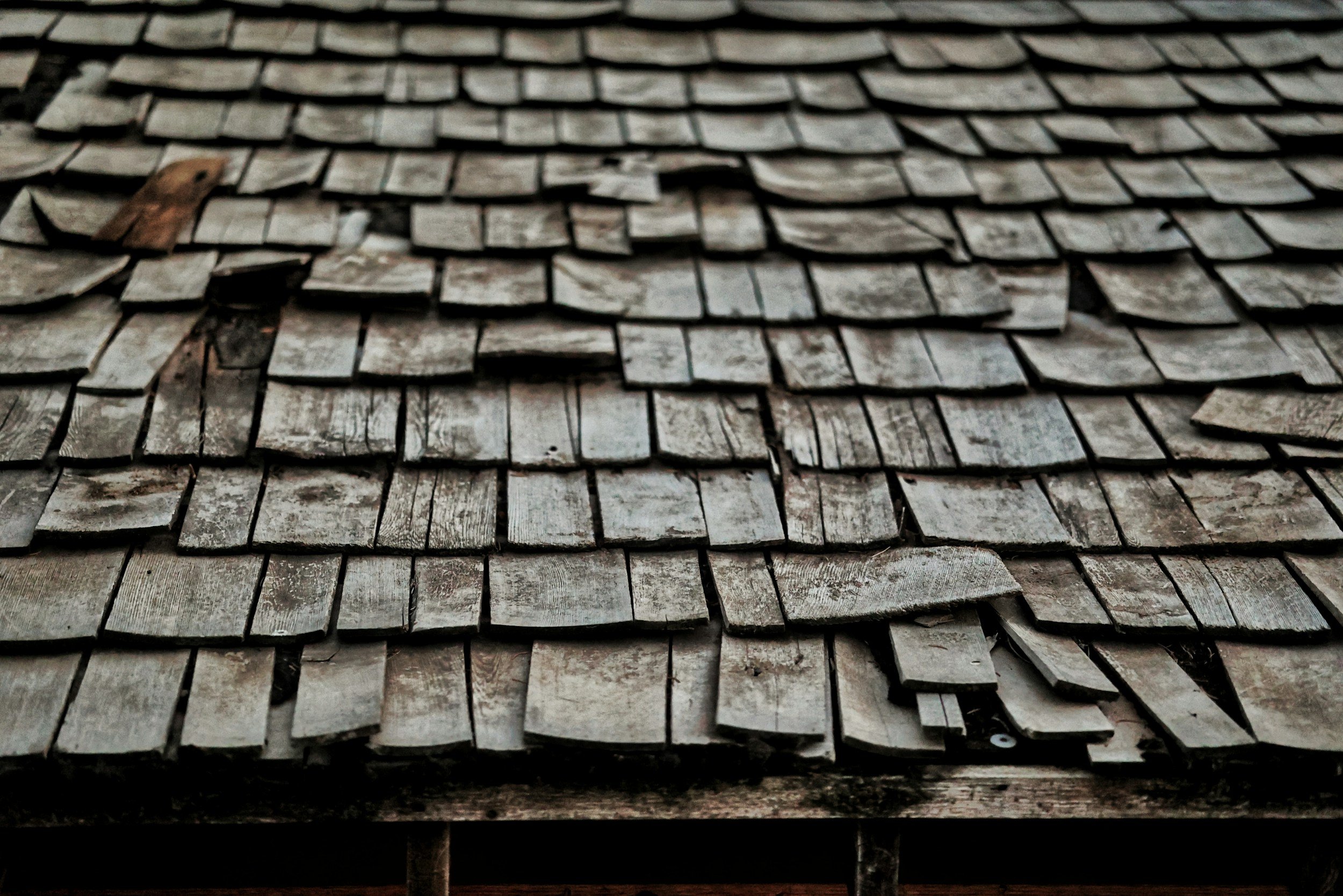 Weathered wood-shake roof with damaged and uneven shingles
