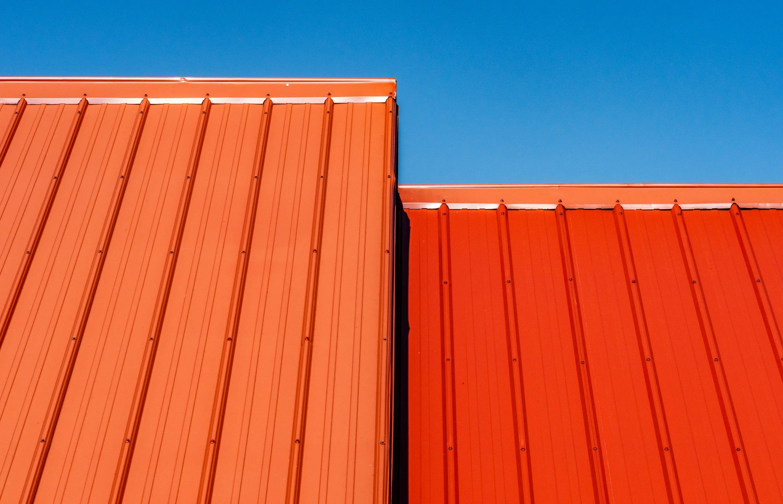 Red standing-seam metal roof against a blue sky