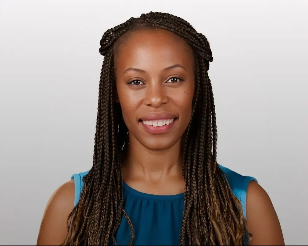 Portrait of a smiling African American woman with braided hair wearing a blue sleeveless top