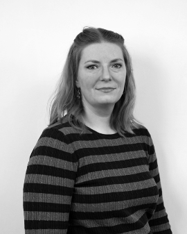 Black and white portrait of a woman with shoulder-length hair, wearing a striped sweater, looking at the camera with a neutral expression.
