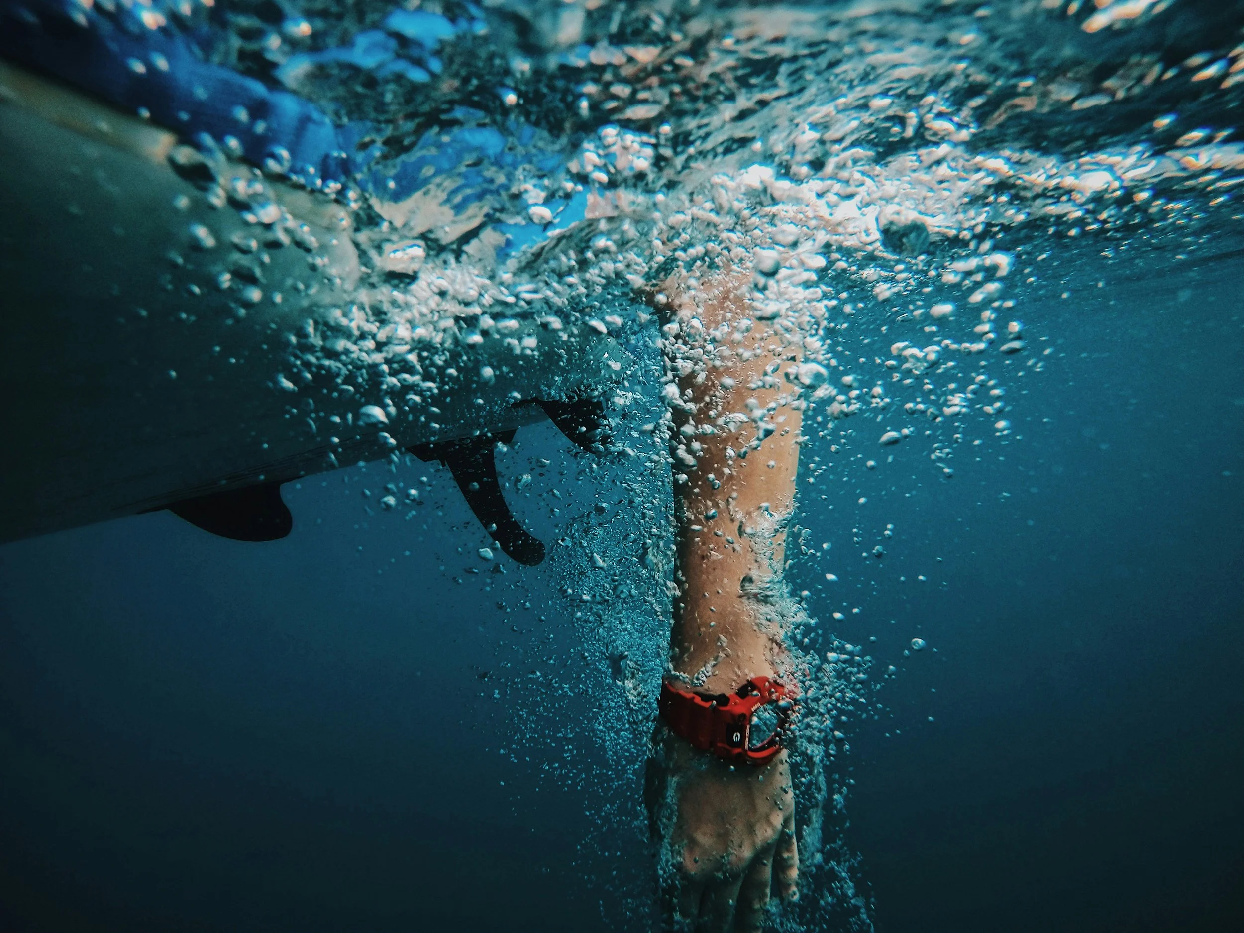 Sea Wisdom luxury post-swim recovery imagery showing an underwater shot of a person in a red life jacket swimming near a boat, with bubbles rising to the surface.
