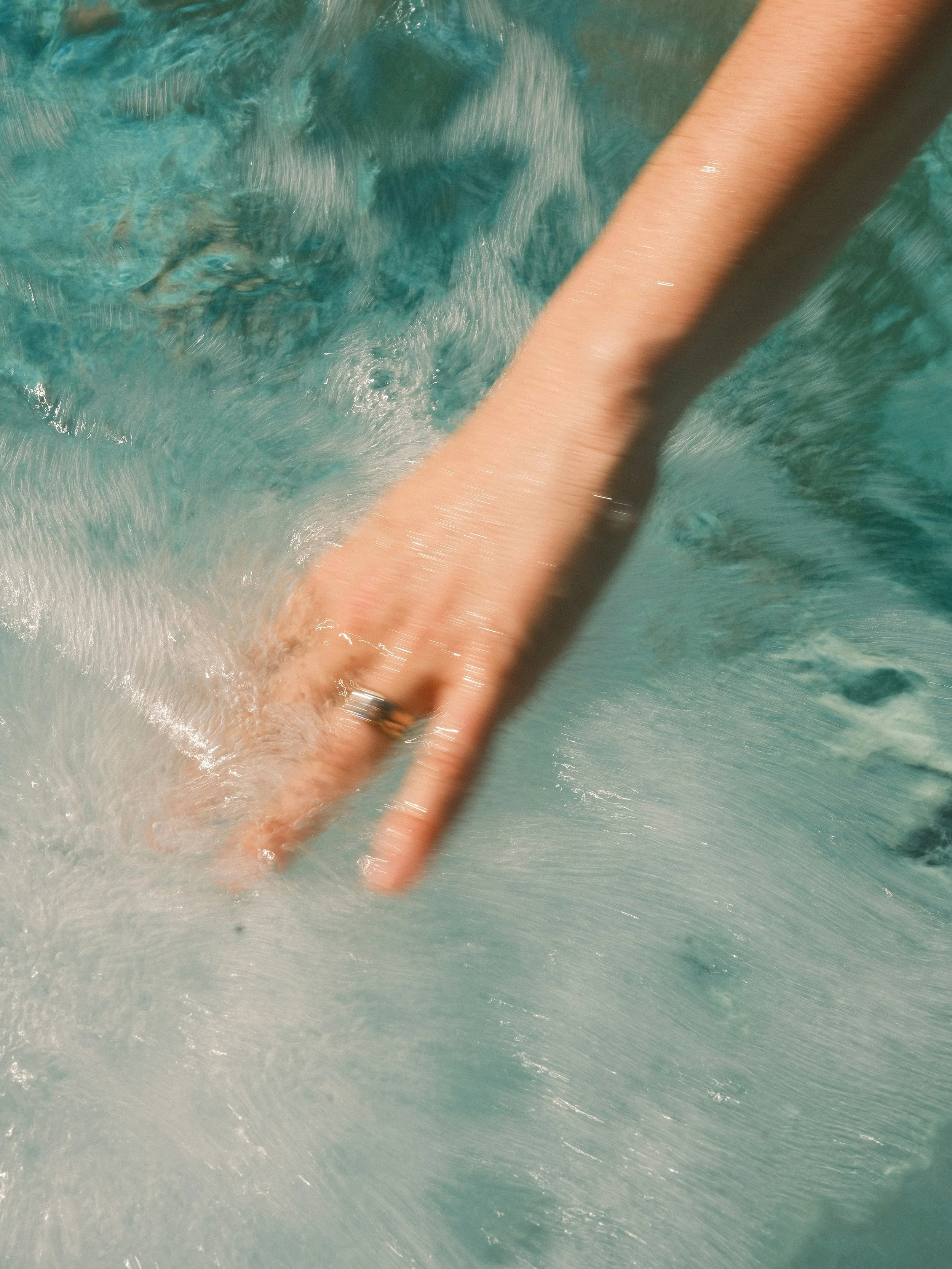 sea-wisdom marine actives ocean-intelligence brand image showing a person's hand submerged in water, with a beige and dark object or tube nearby.