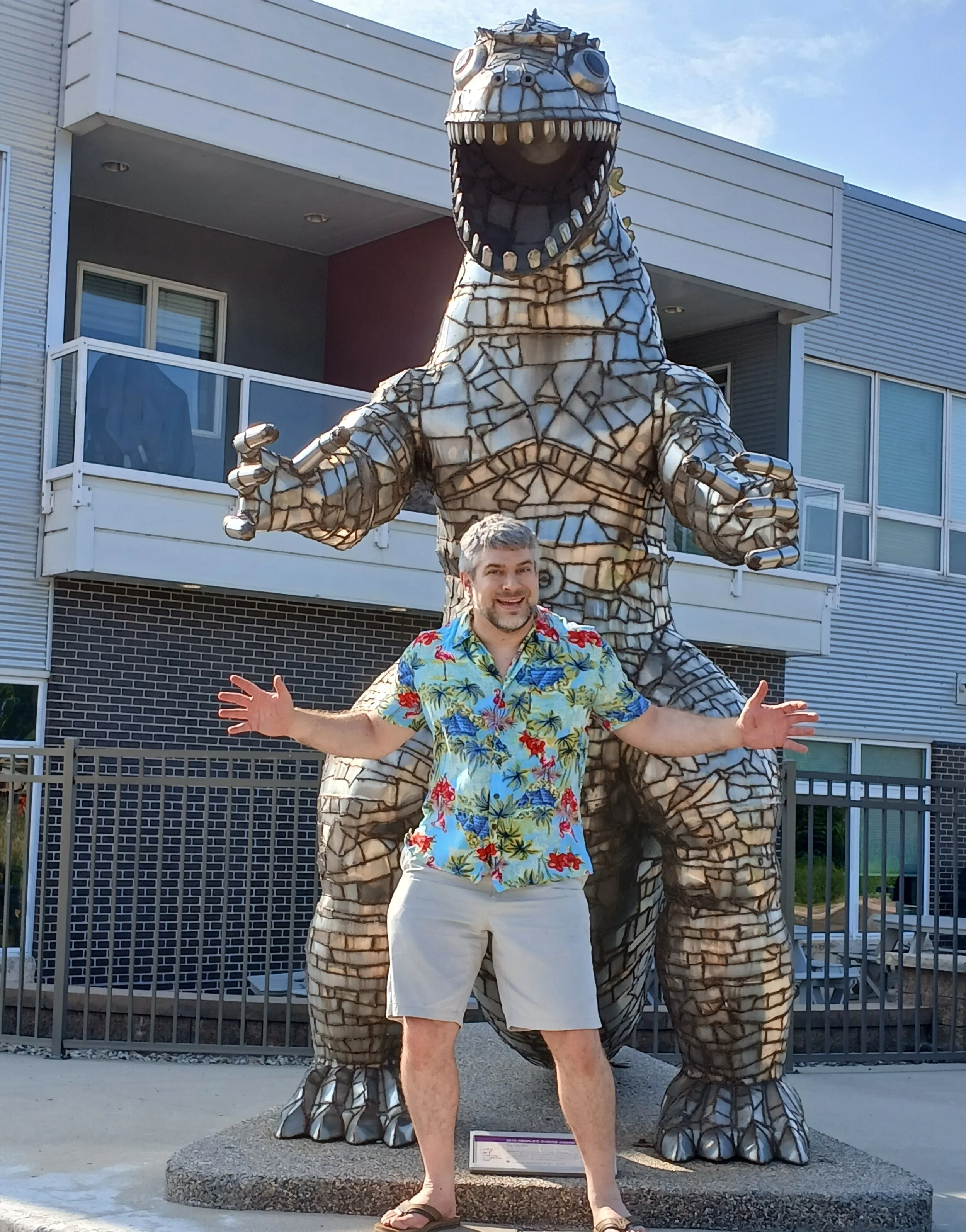 Benton standing in front of the Godzilla statue copying its pose