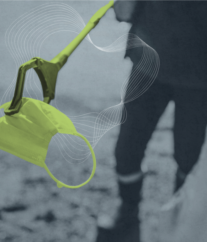 A face mask hanging from a grabber tool with a person in the background, outdoors, in a grayscale setting with abstract white line patterns.