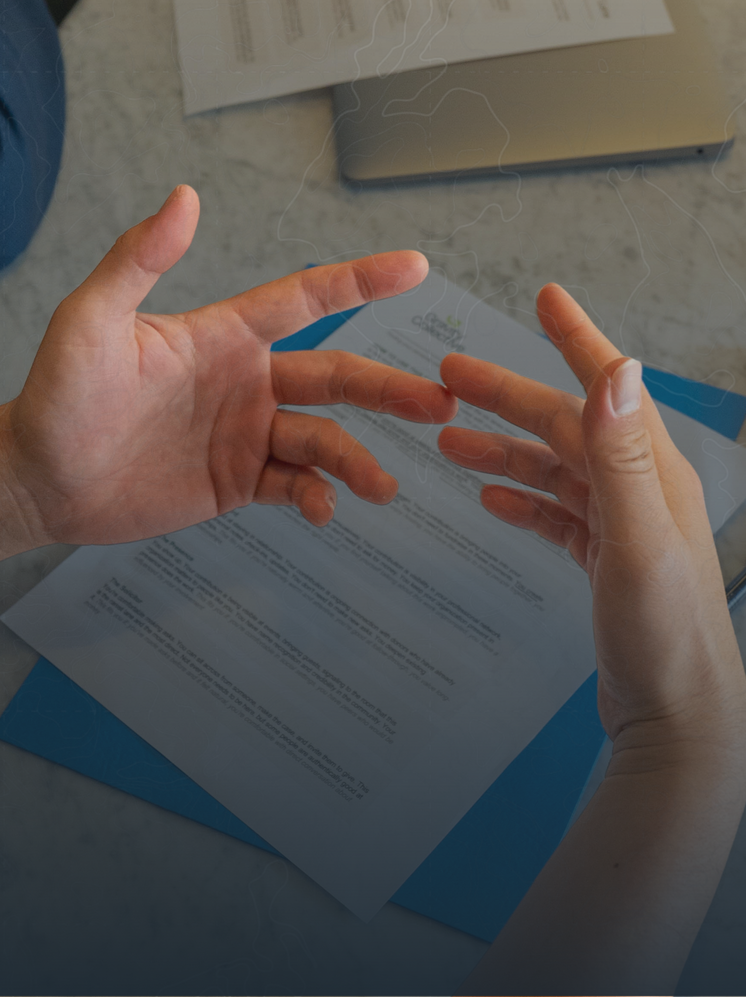 Two hands with light skin tone are shown gesturing towards each other over a pair of documents on a table. The documents contain printed text and graphics, possibly instructions or information sheets. There's a blue folder or binder beneath the documents.