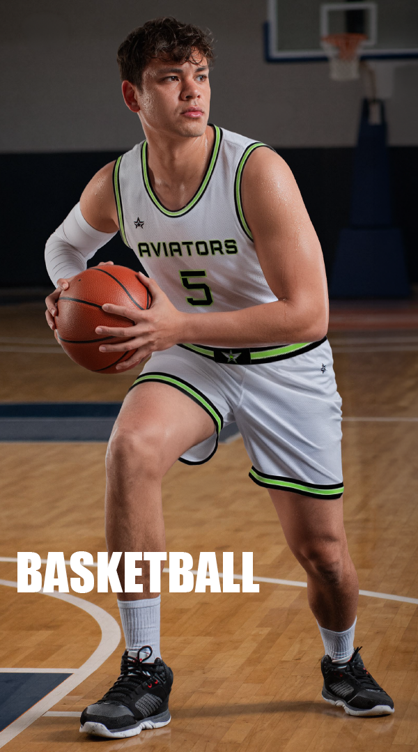 Young male basketball player in white uniform holding a basketball on a court.