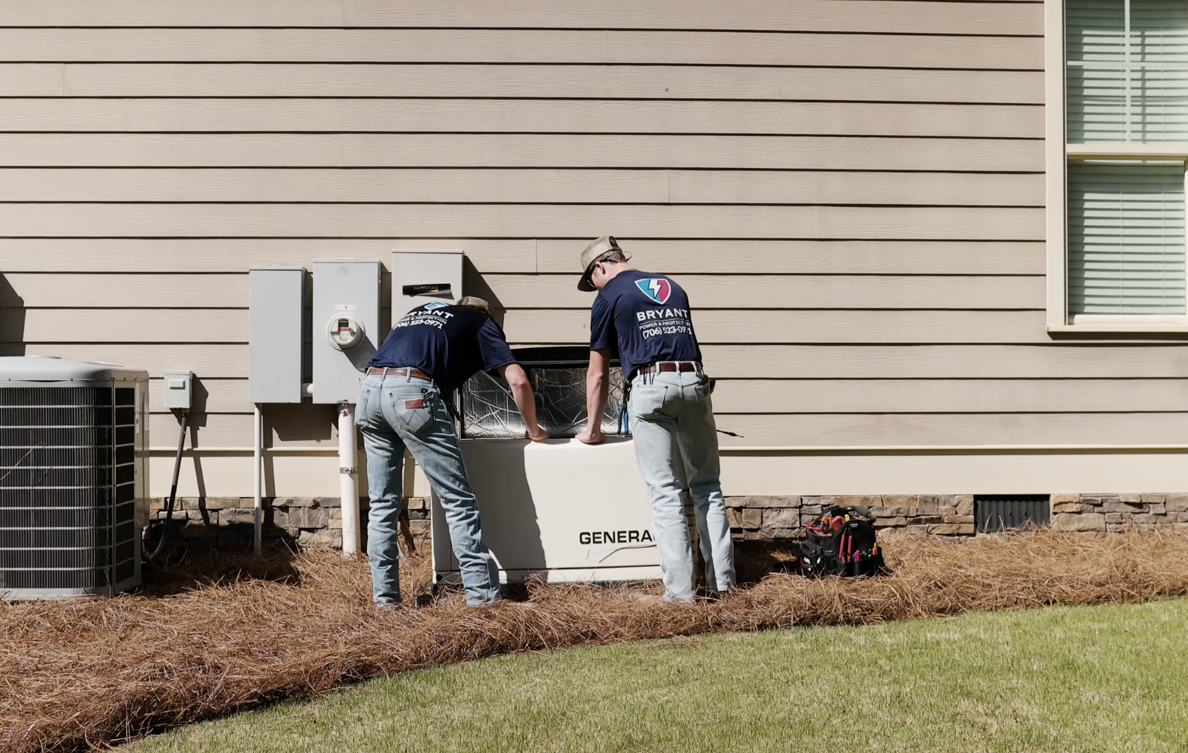Two technicians working on a generator outside a residential building, with tools and equipment nearby.