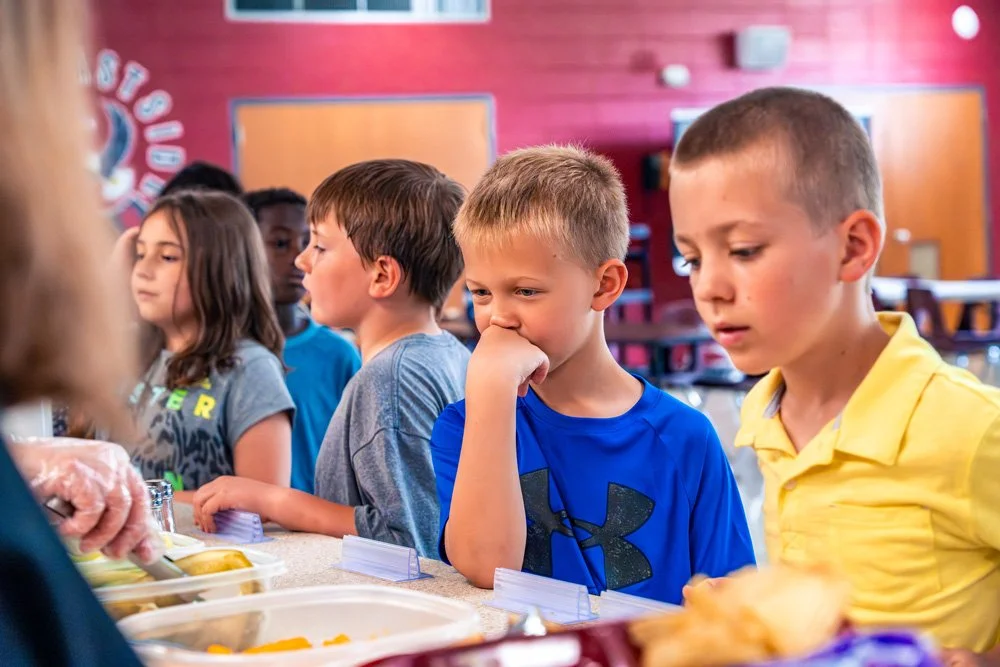 Children in line at a cafeteria serving food.