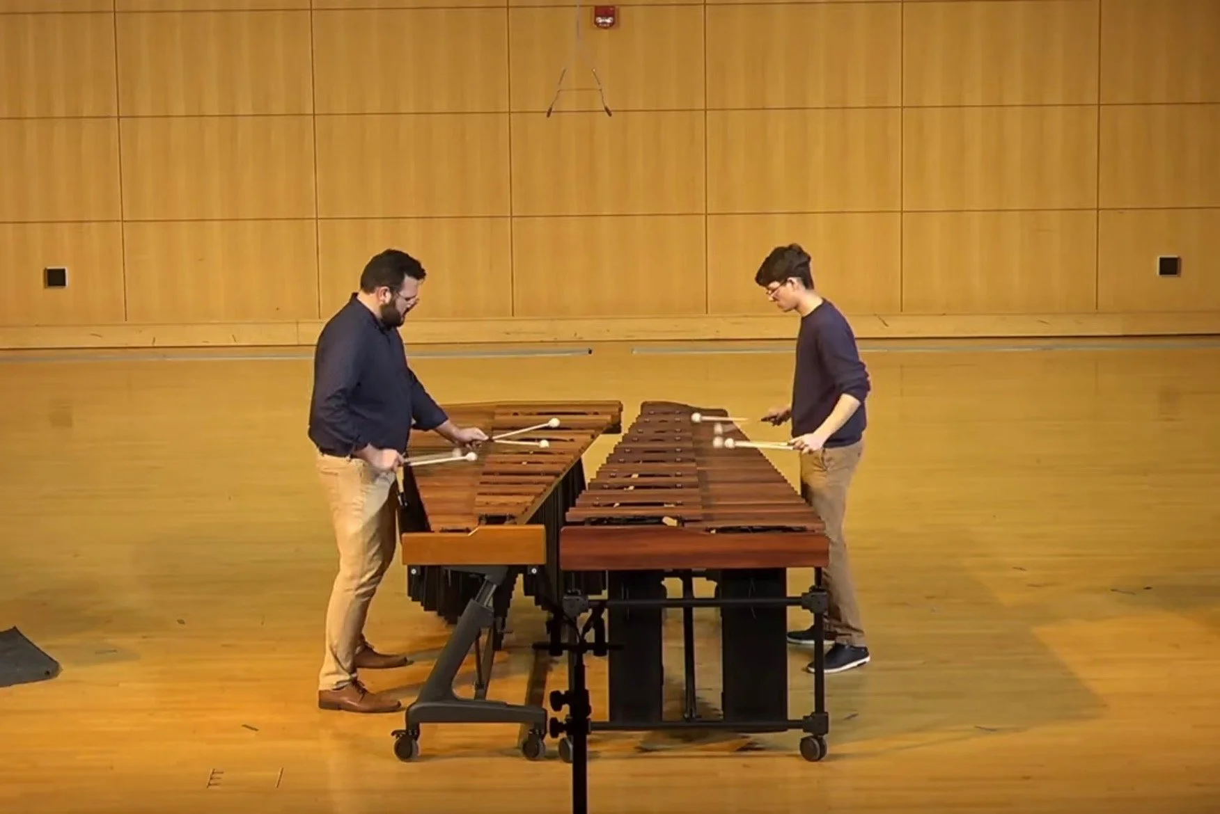 Playing xylophone in a large indoor space with wooden wall panels.