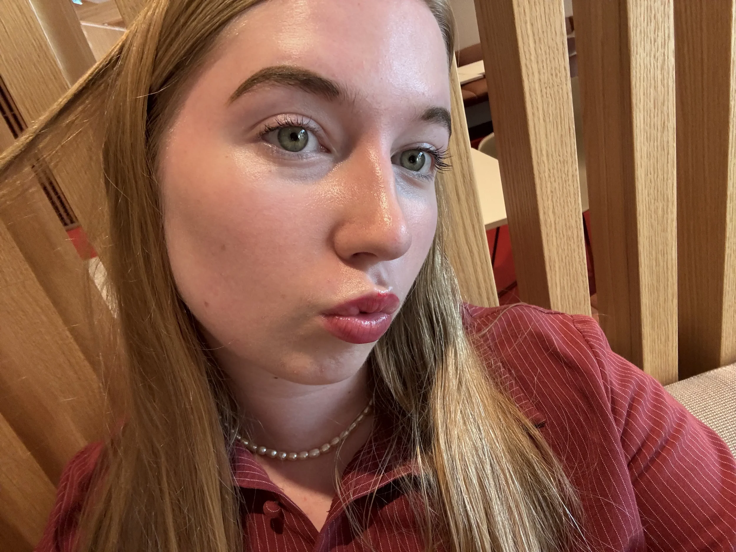 A young lady in blond with blue eyes showing her lips weariing Conditioning Lip Gloss in Strawberry, pink shade.