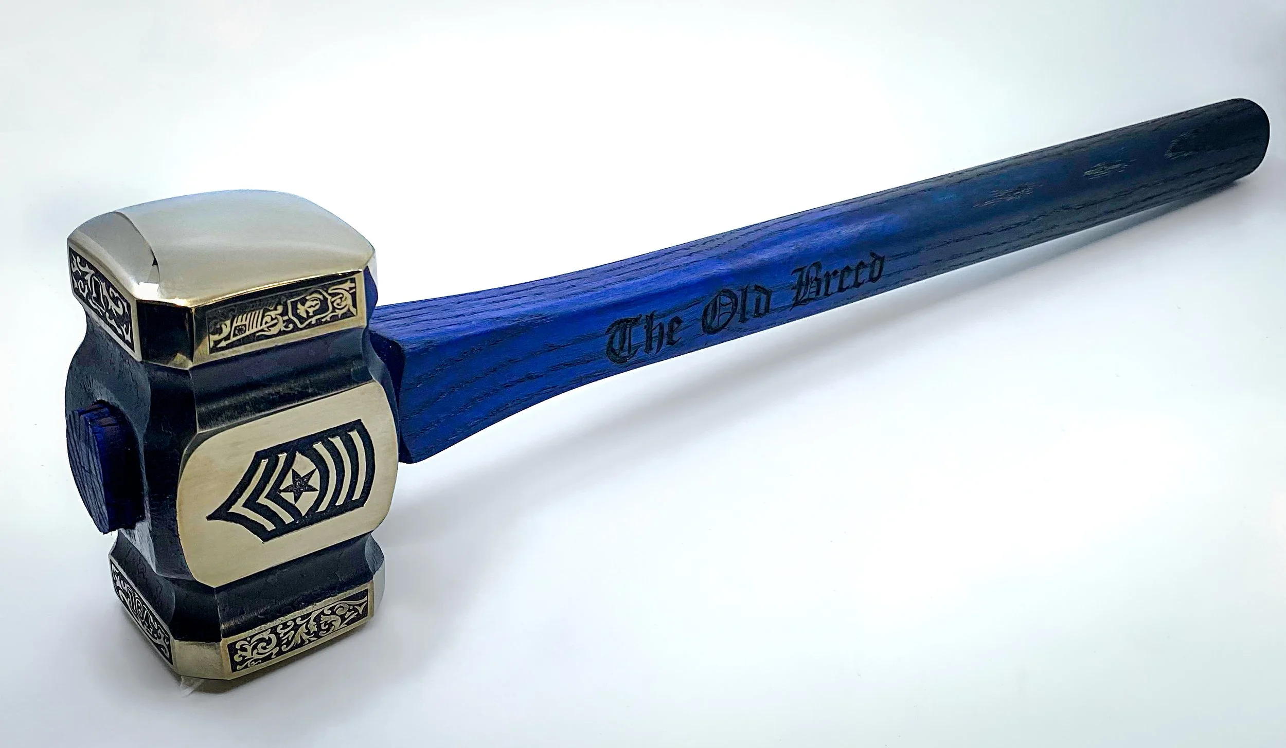 A Forged and engraved hammer with a black and gold decorated head and a dark blue wooden handle engraved with 'The Old Breed' on a white background. For the USMC.