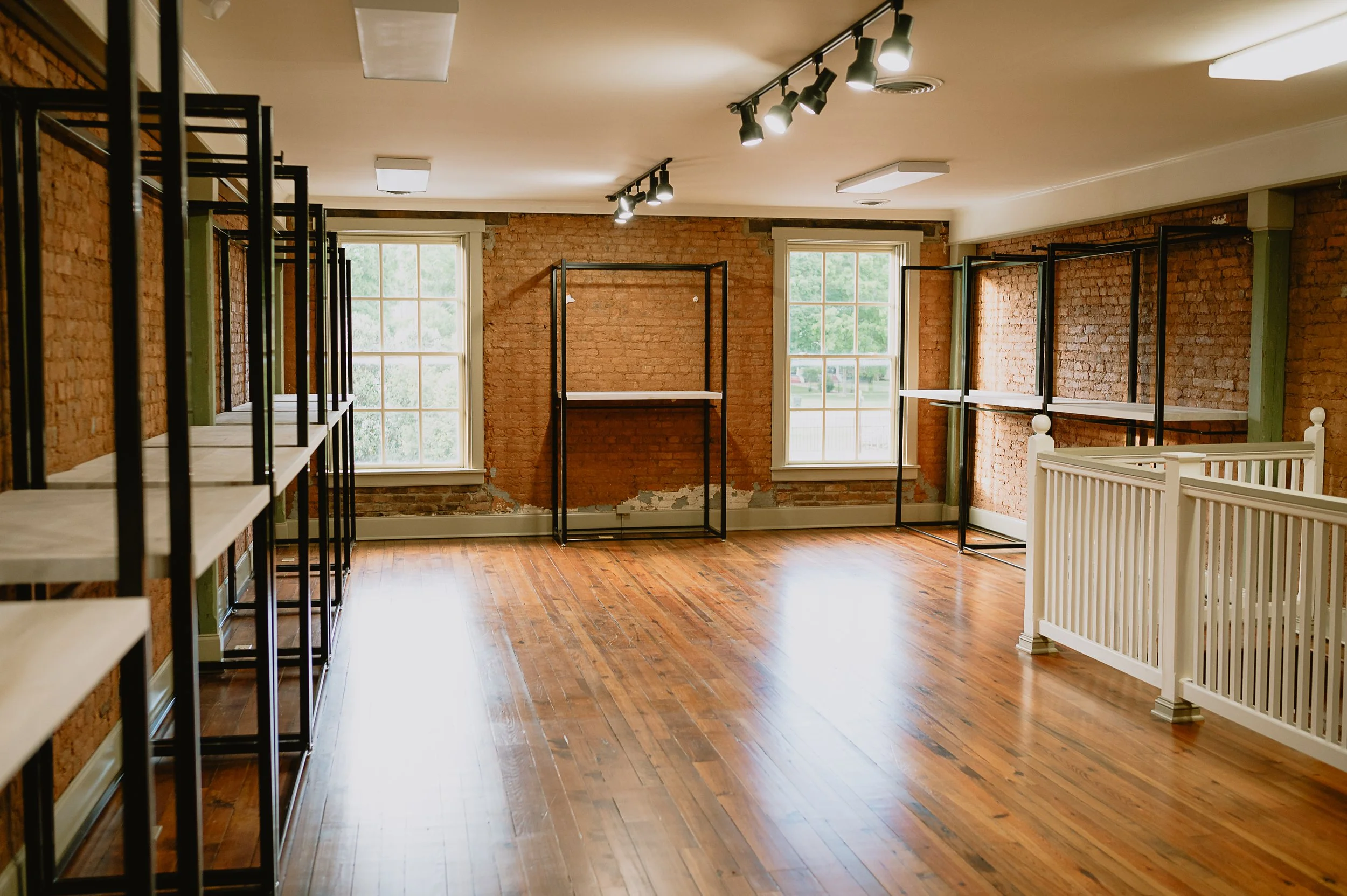 Empty room with brick walls, large windows, and metal shelving units.