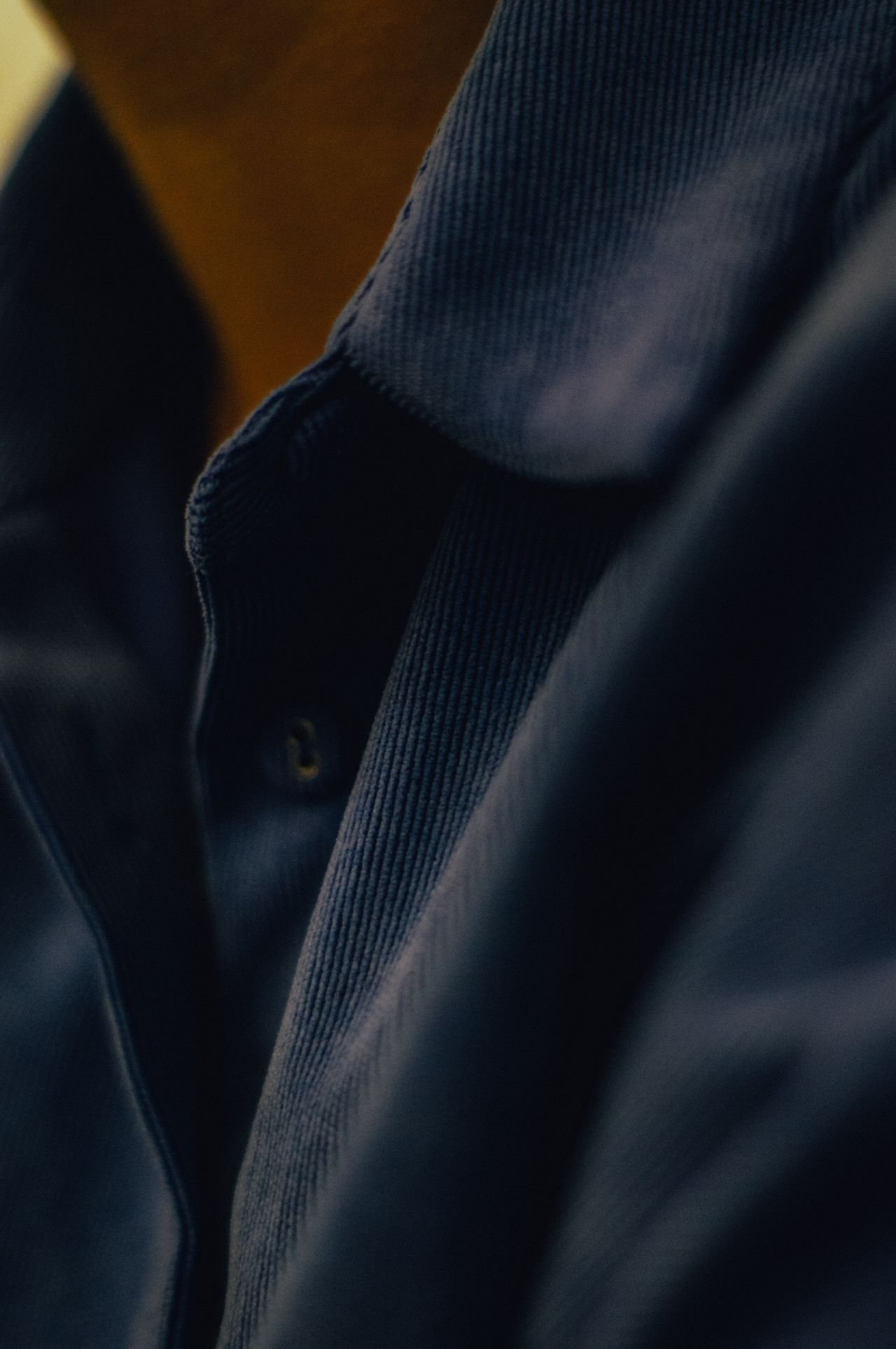 Close-up of dark blue and black clothing fabric, showing textured and smooth parts.