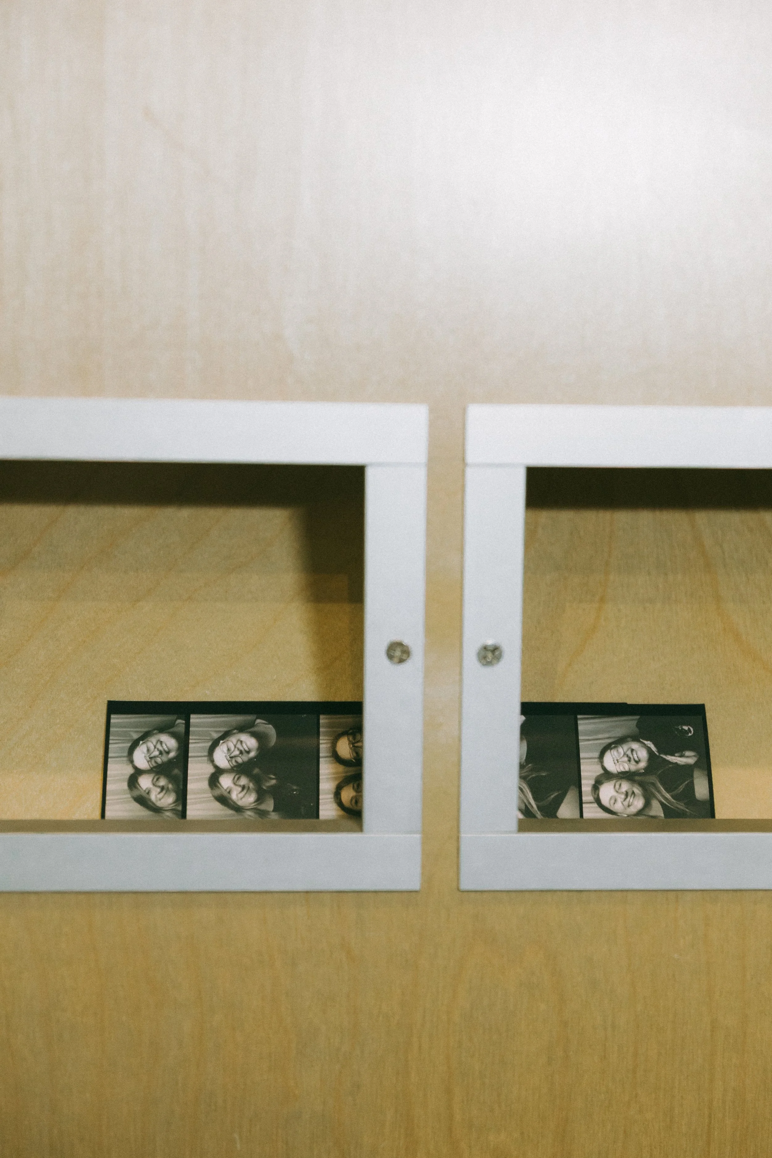 photo booth strip photos of two women smiling, placed on a light-colored wooden floor.