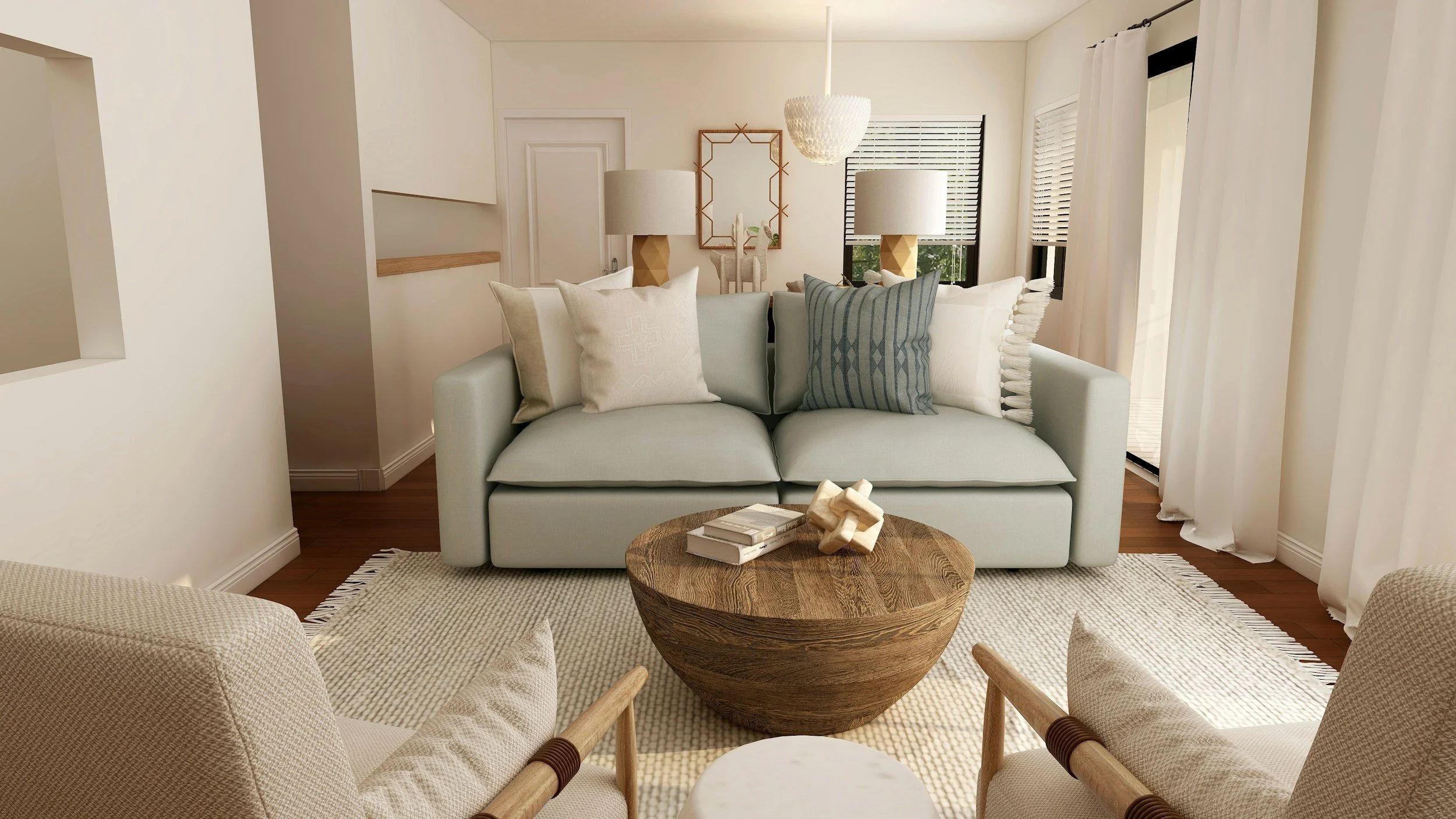 A living room with a light green couch and multiple throw pillows, round wooden coffee table with books and decorative objects, two armchairs with woven upholstery, and a pair of matching table lamps with beige shades, near windows with white blinds and curtains.