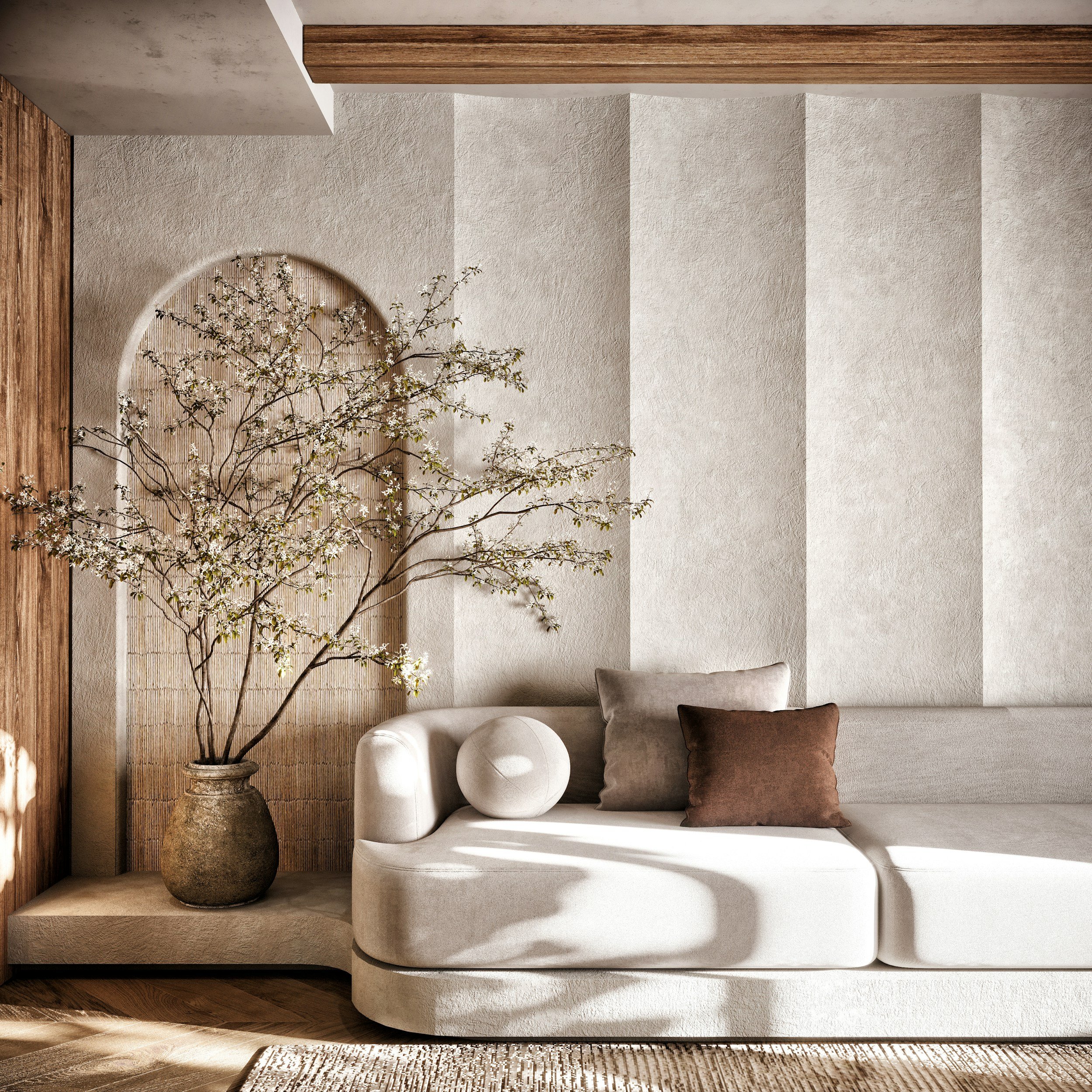 Living room with a white curved sofa, a textured wall, a large potted plant with white blossoms, wooden flooring, and a decorative rug.