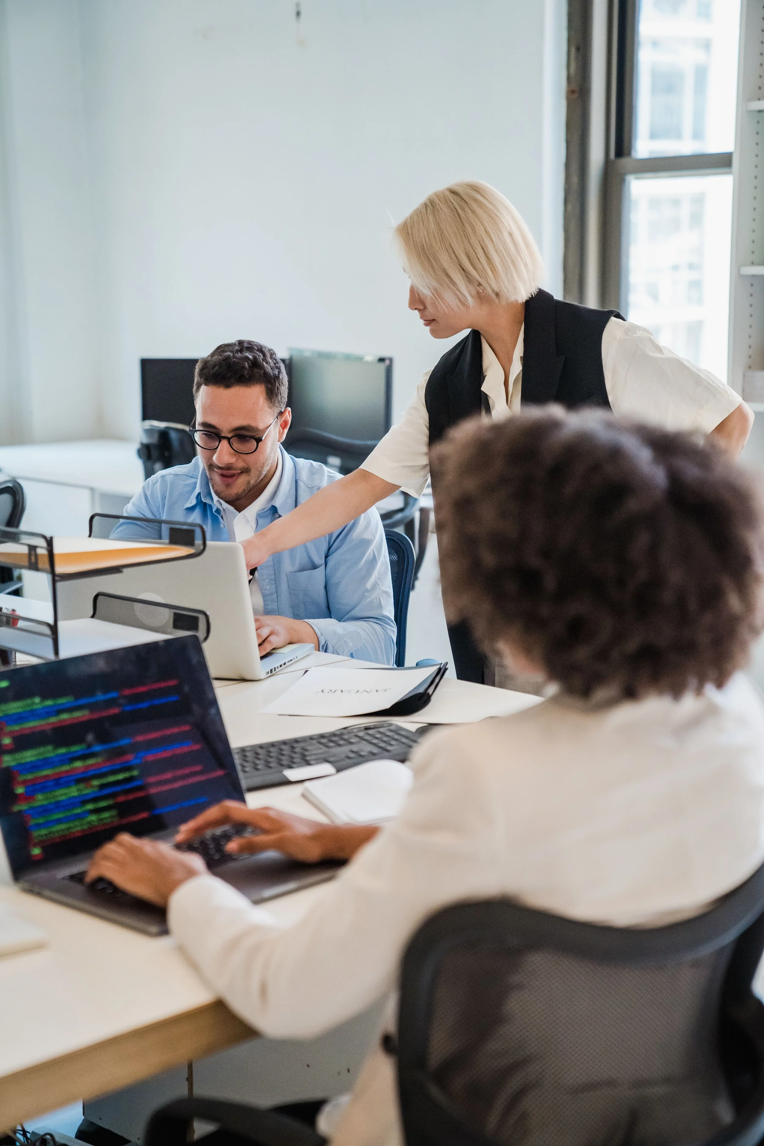 Colleagues discussing work beside a computer in a shared office.