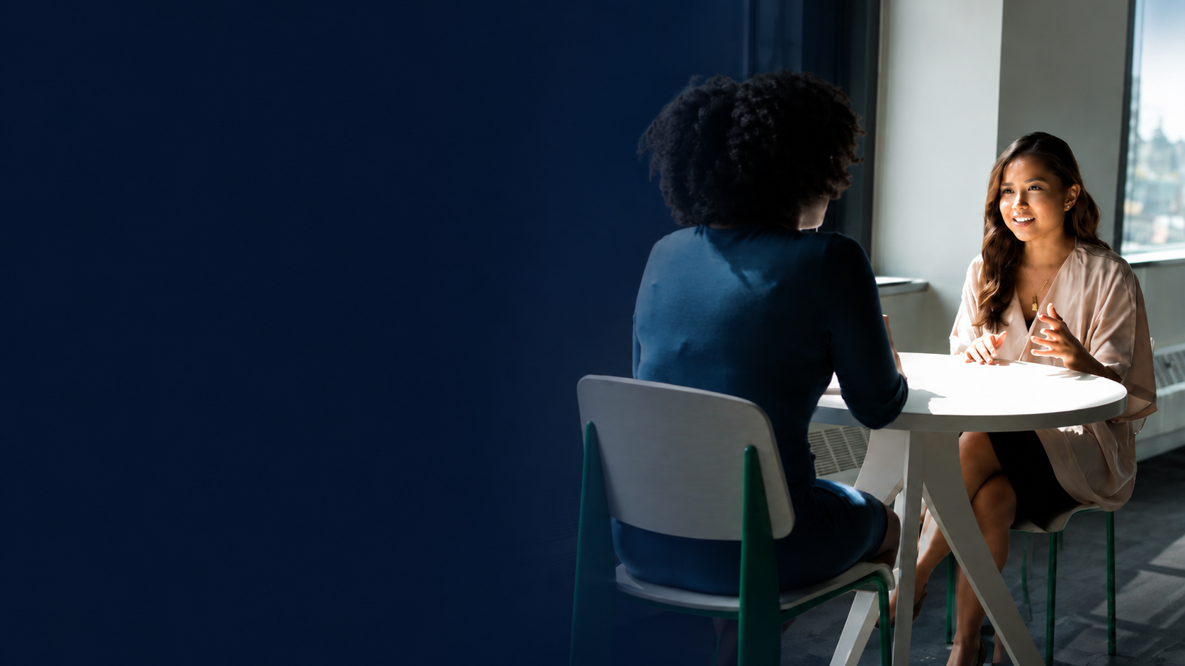 Two professionals having a one-to-one conversation in a bright office.