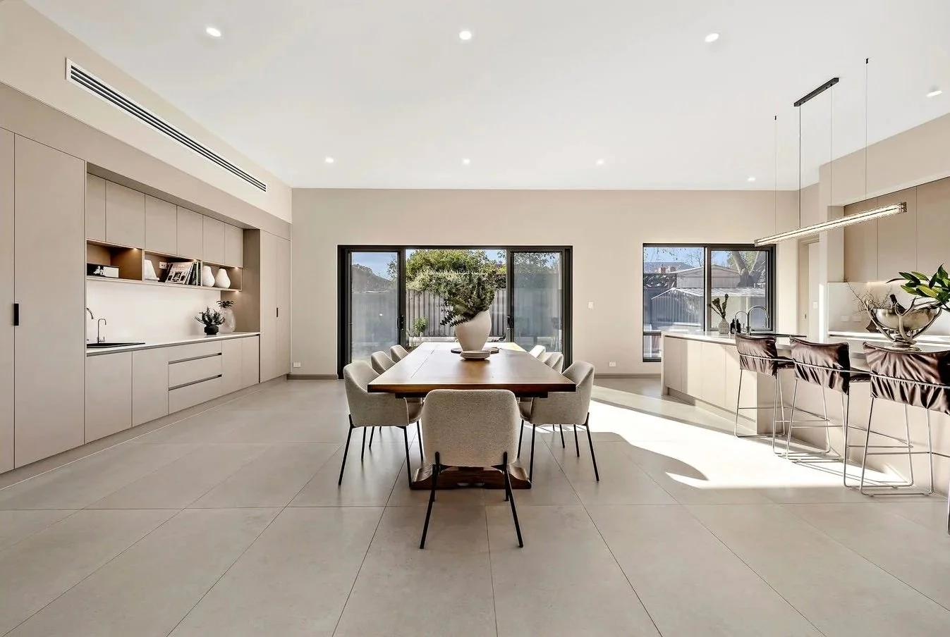 Modern dining and kitchen area with large windows, neutral colors, and minimalistic decor.