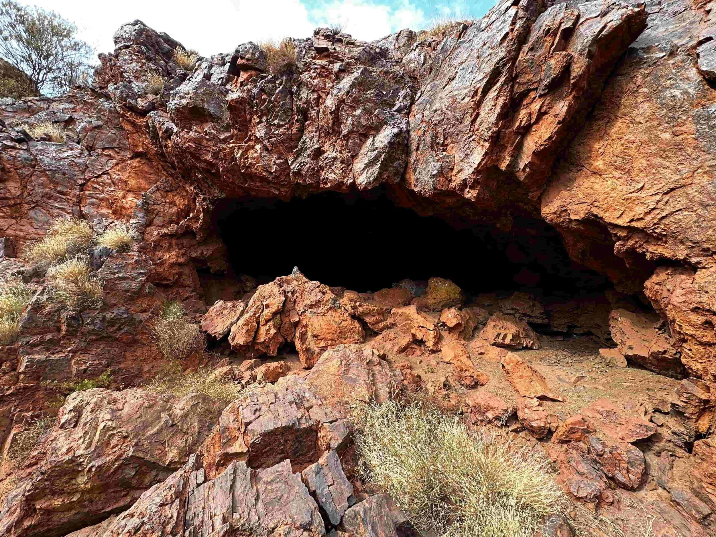 Rugged, reddish-brown rocky hillside with sparse desert vegetation.