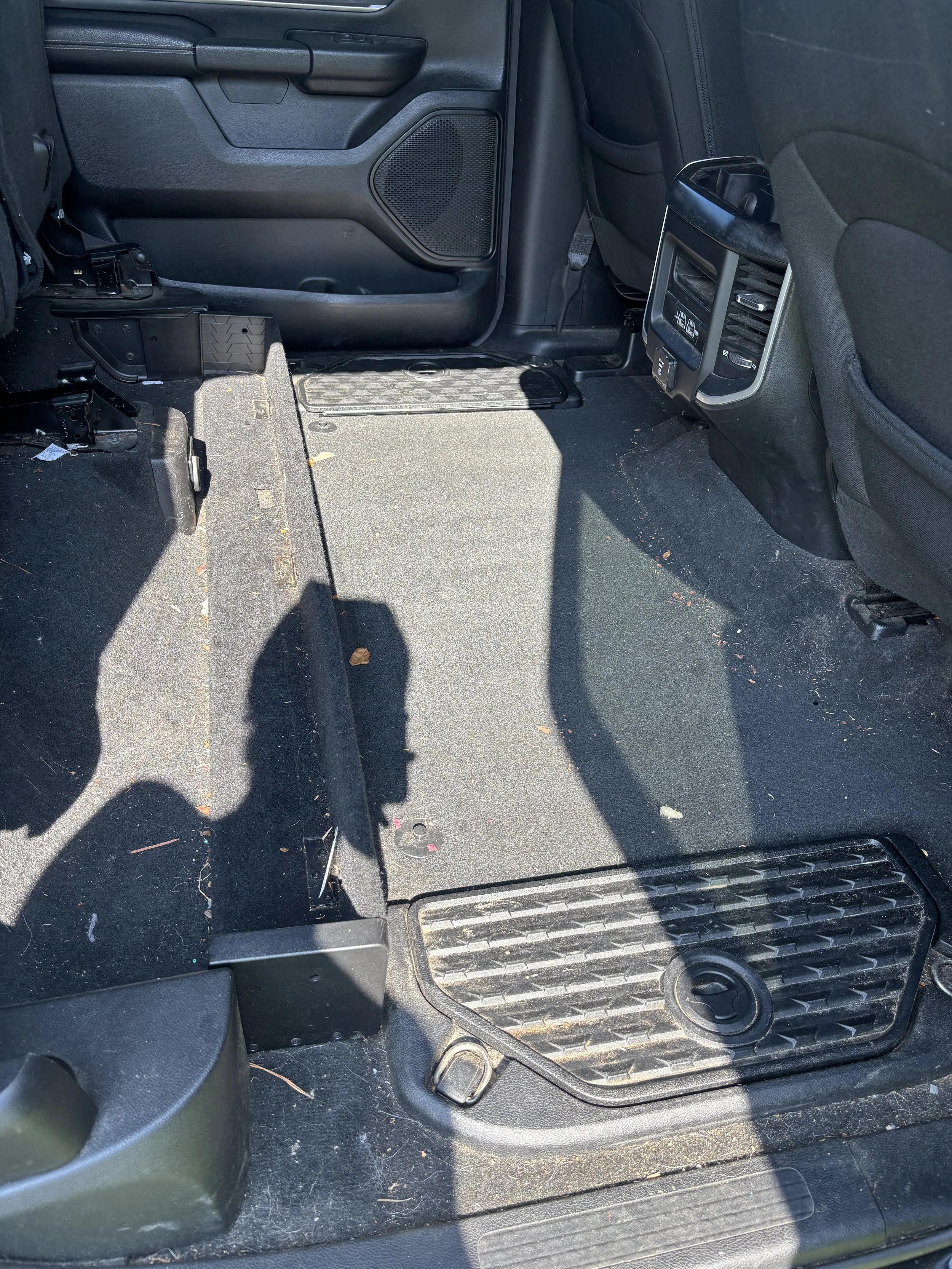 Interior of a vehicle showing the back seat area with a missing seat and exposed floor, side panel, and vent.