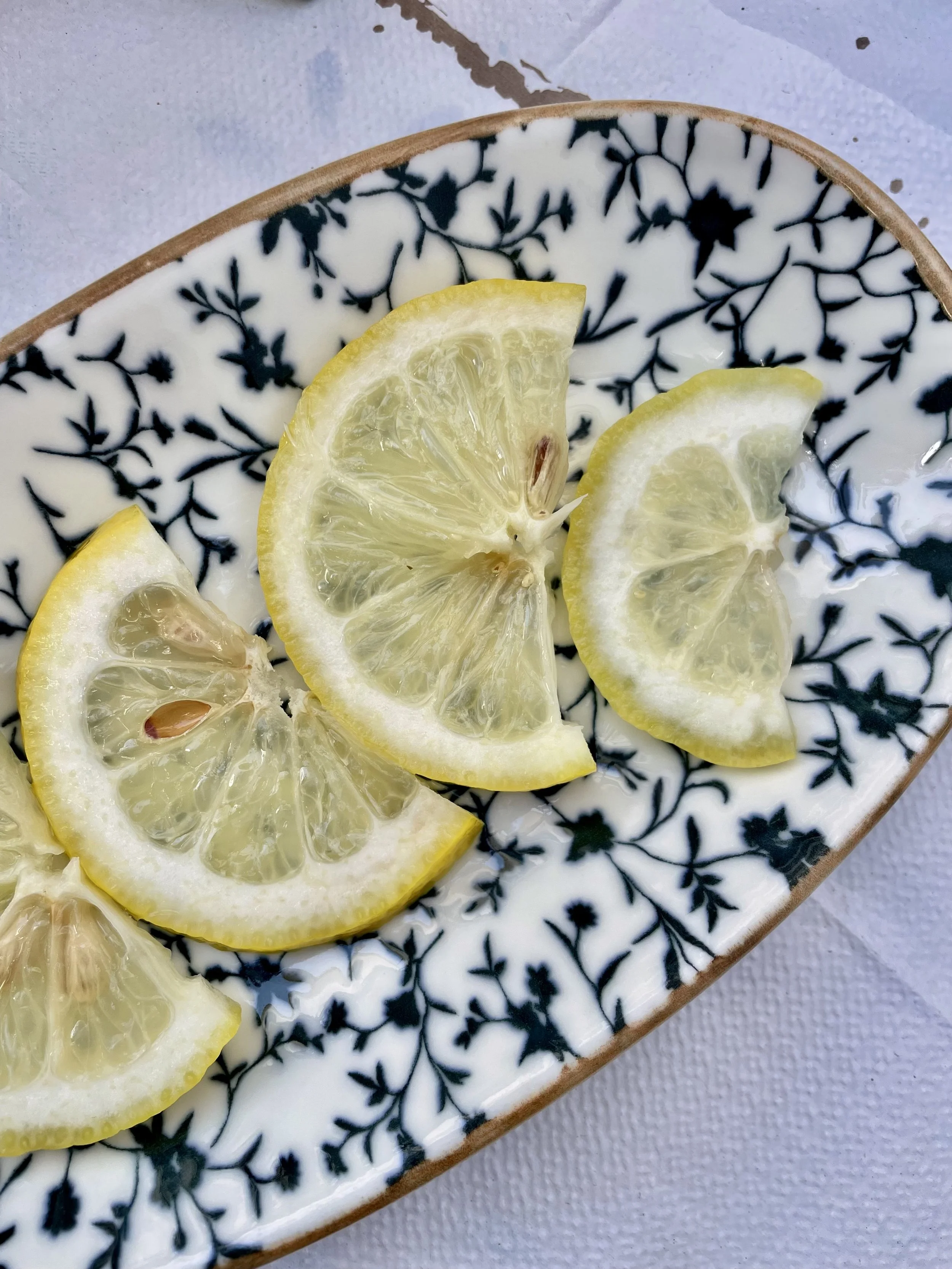 Close-up of lemon slices on a decorative black-and-white patterned ceramic plate.
