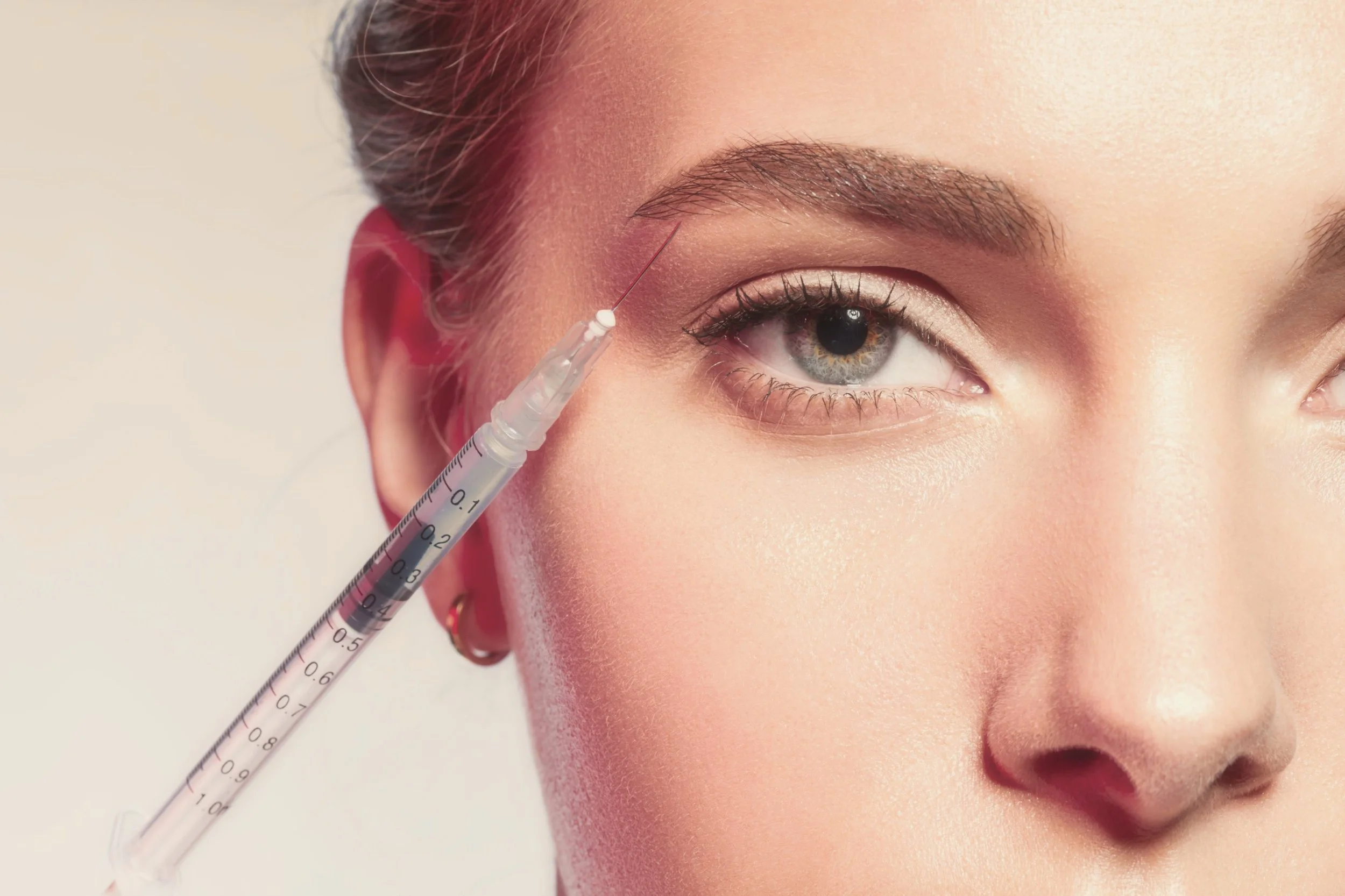 Close-up of a woman receiving a Brow Lift injection near the outer brow. Links to Brow Lift treatment