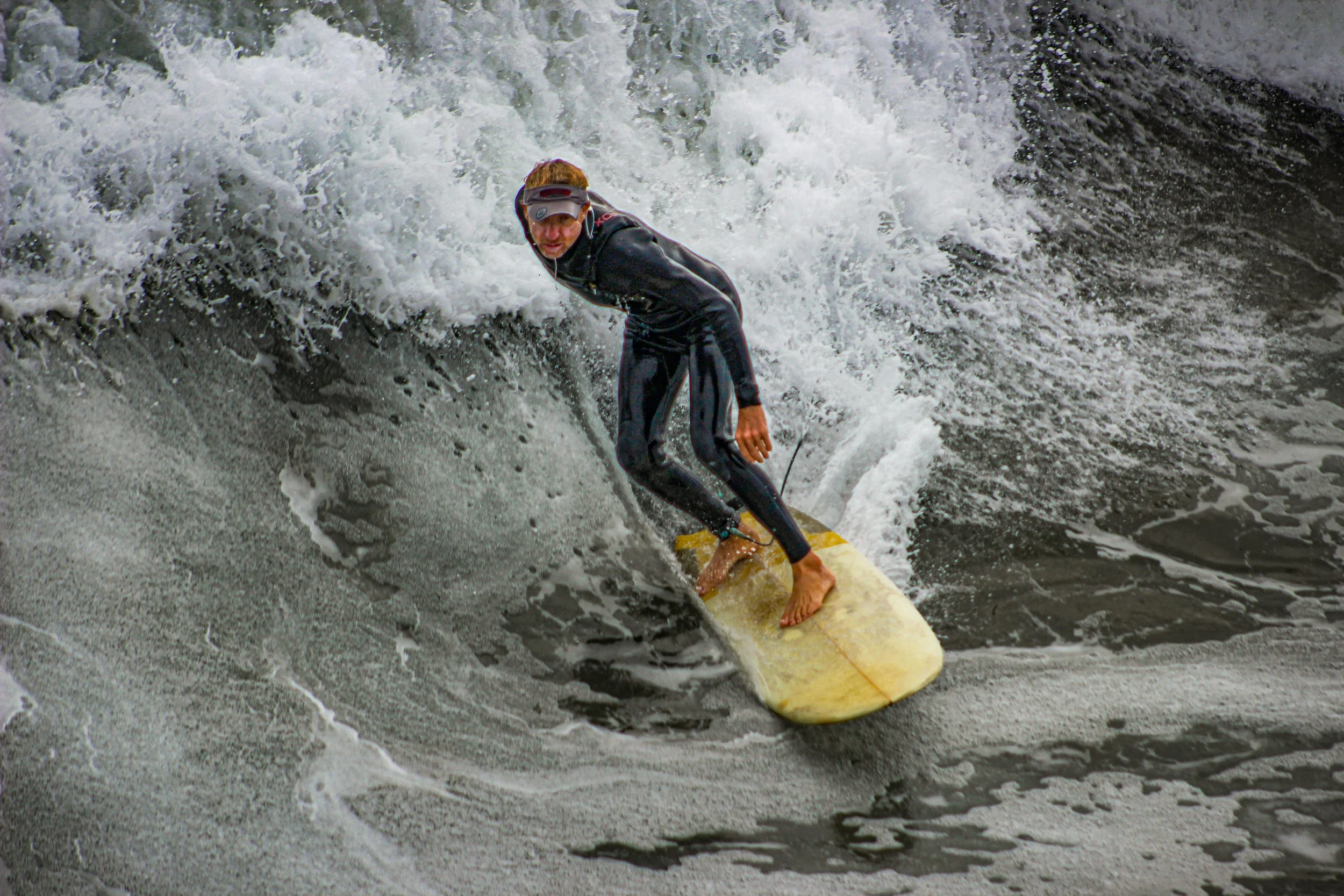 A man surfing on a yellow surfboard in a wave.