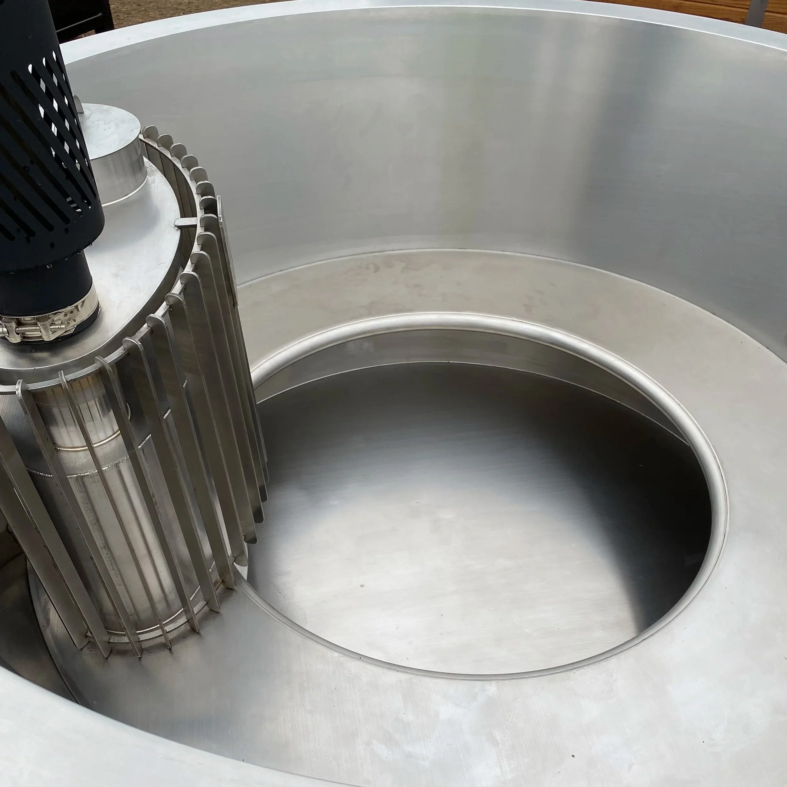 Close-up of stainless steel insert in wood fired hot tub, featuring a round stainless bench seat