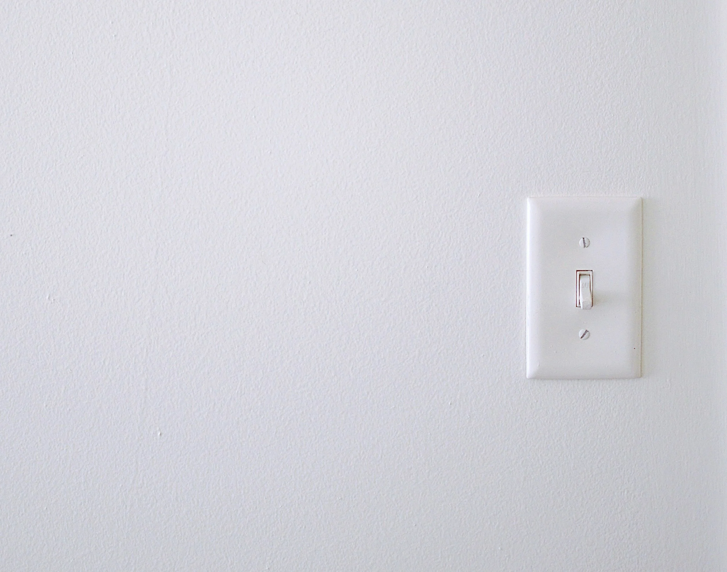 白い壁に取り付けられた電気のスイッチとコンセント。