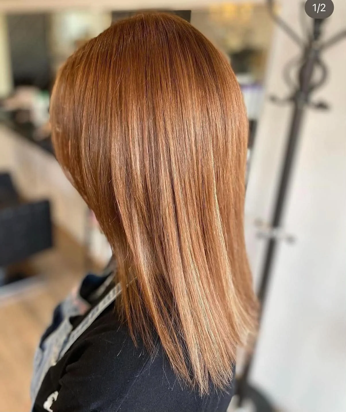 Back view of a person with straight, vibrant red hair styled in a sleek, layered cut.