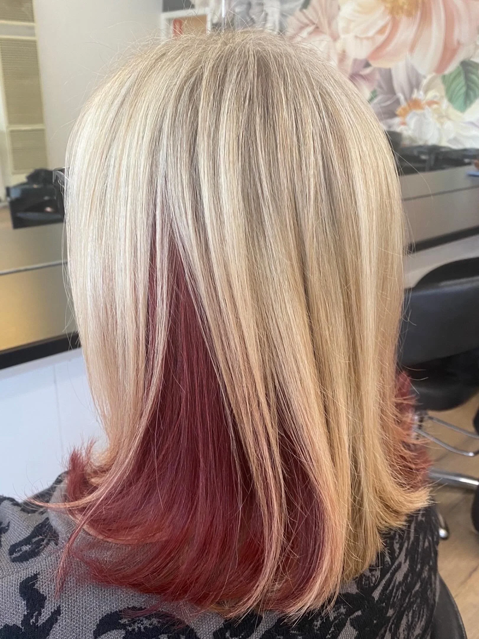 A person's hair with platinum blonde with pinkish-red tips, styled straight, with a blurred background.