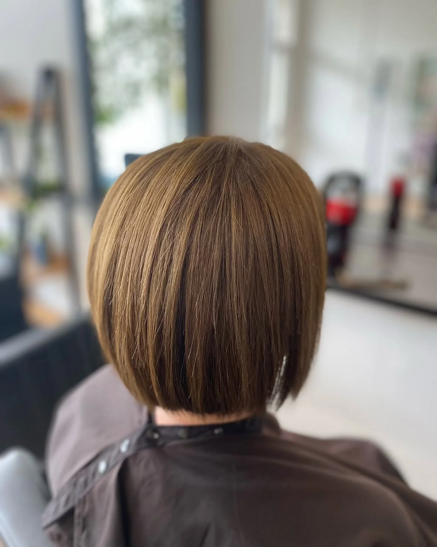 A person with short, straight, light brown hair sitting in a salon or barbershop.