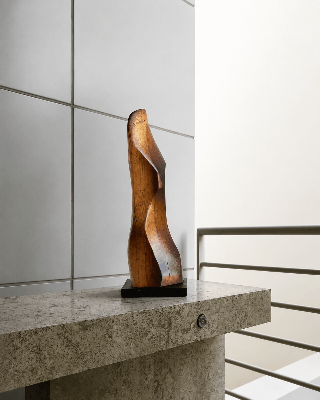 Duality of Being, hand-carved polished timber sculpture by Ole Jensen on a dark base displayed on a stone ledge in a modern architectural setting