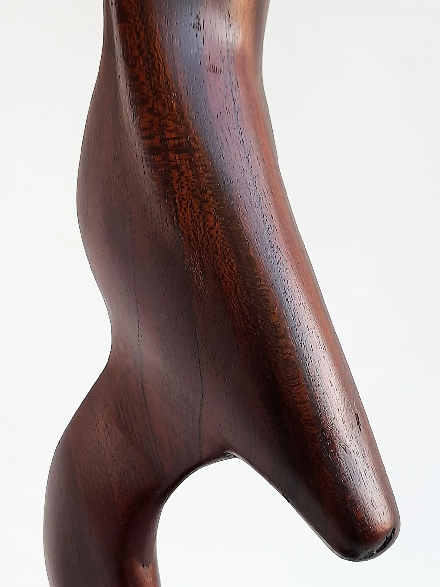 Close-up detail of Poise timber sculpture displaying subtle carved contours, smooth satin finish, and flowing red brown wood grain.