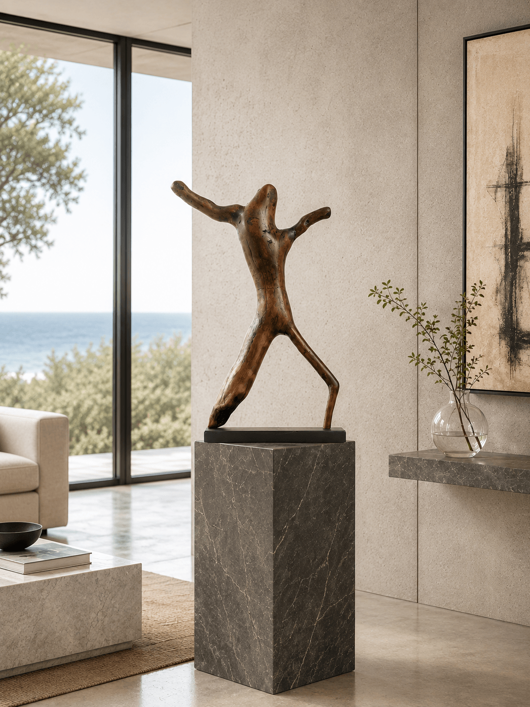 The abstract wood sculpture Alien Dancer, displayed on a tall dark grey marble plinth in a contemporary coastal home with ocean views and a minimalist design.