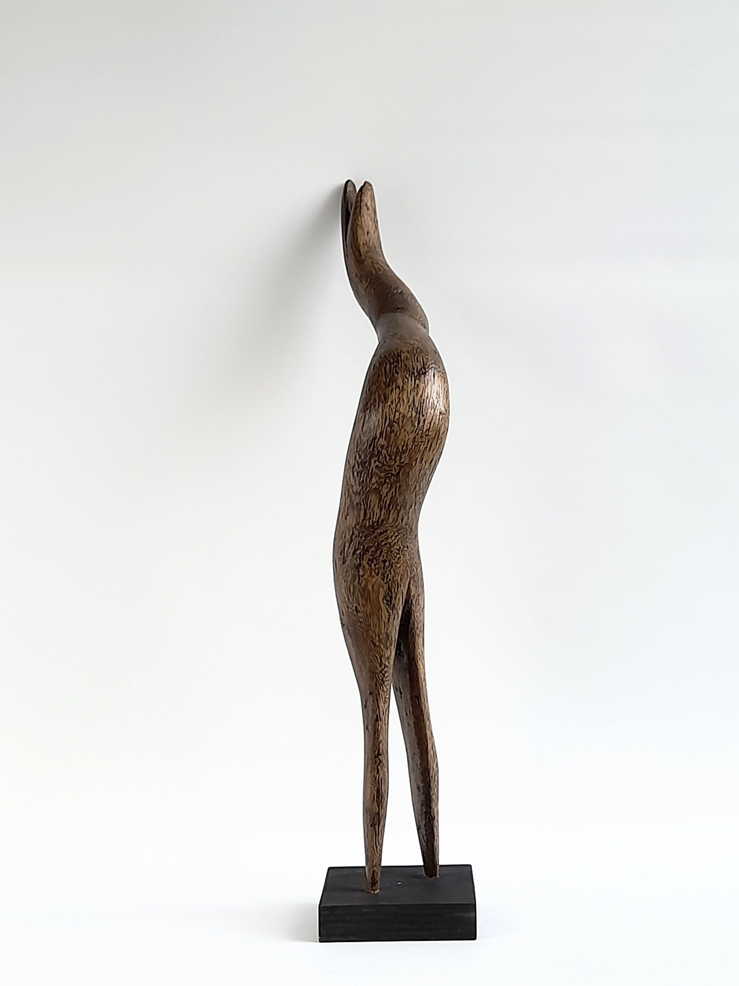 Carved wooden sculpture titled Strive, featuring soaring abstract curves inspired by the fluid form of a bird.