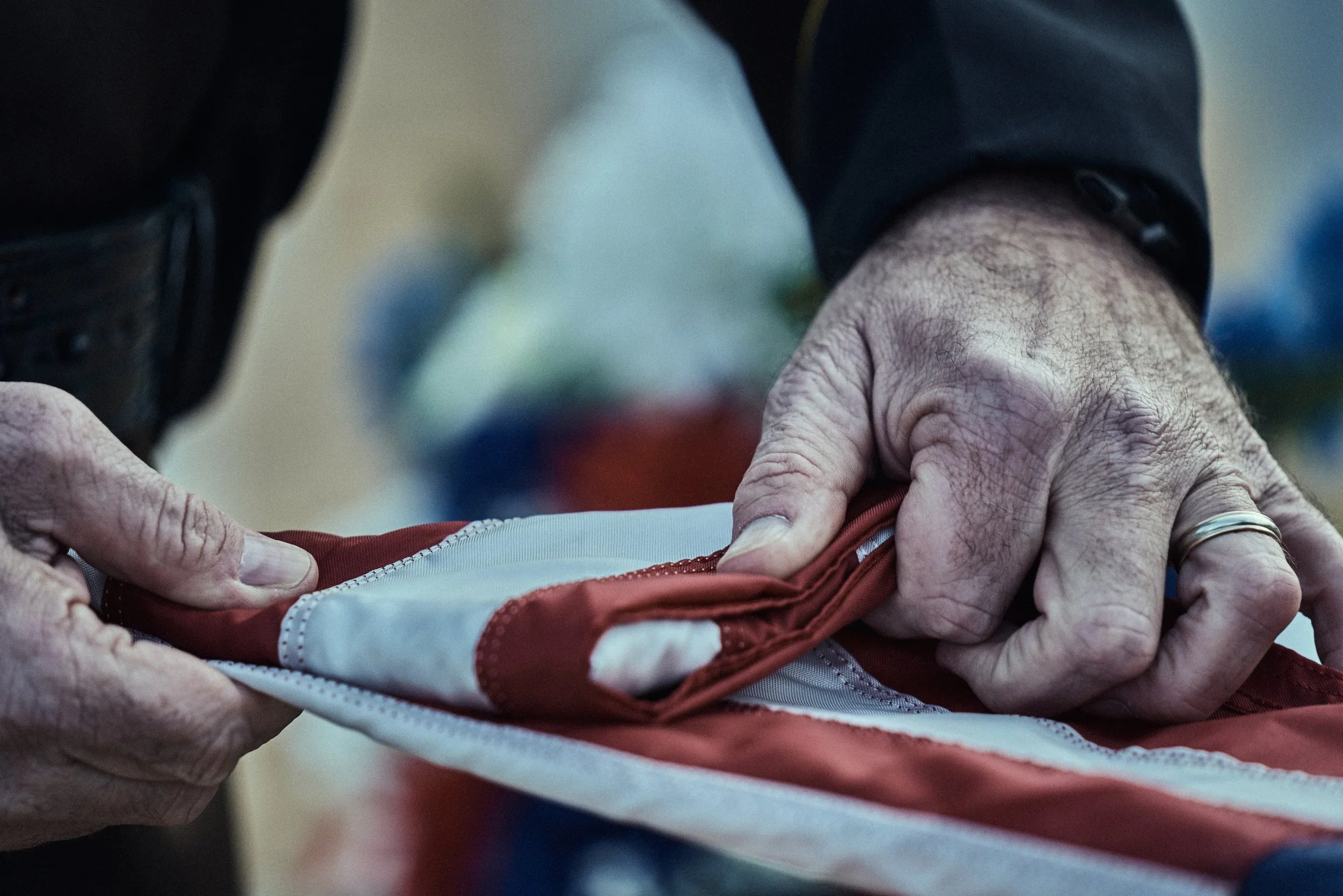 Close-up of a person’s hands adjusting a piece of fabric or clothing, with a blurred background.