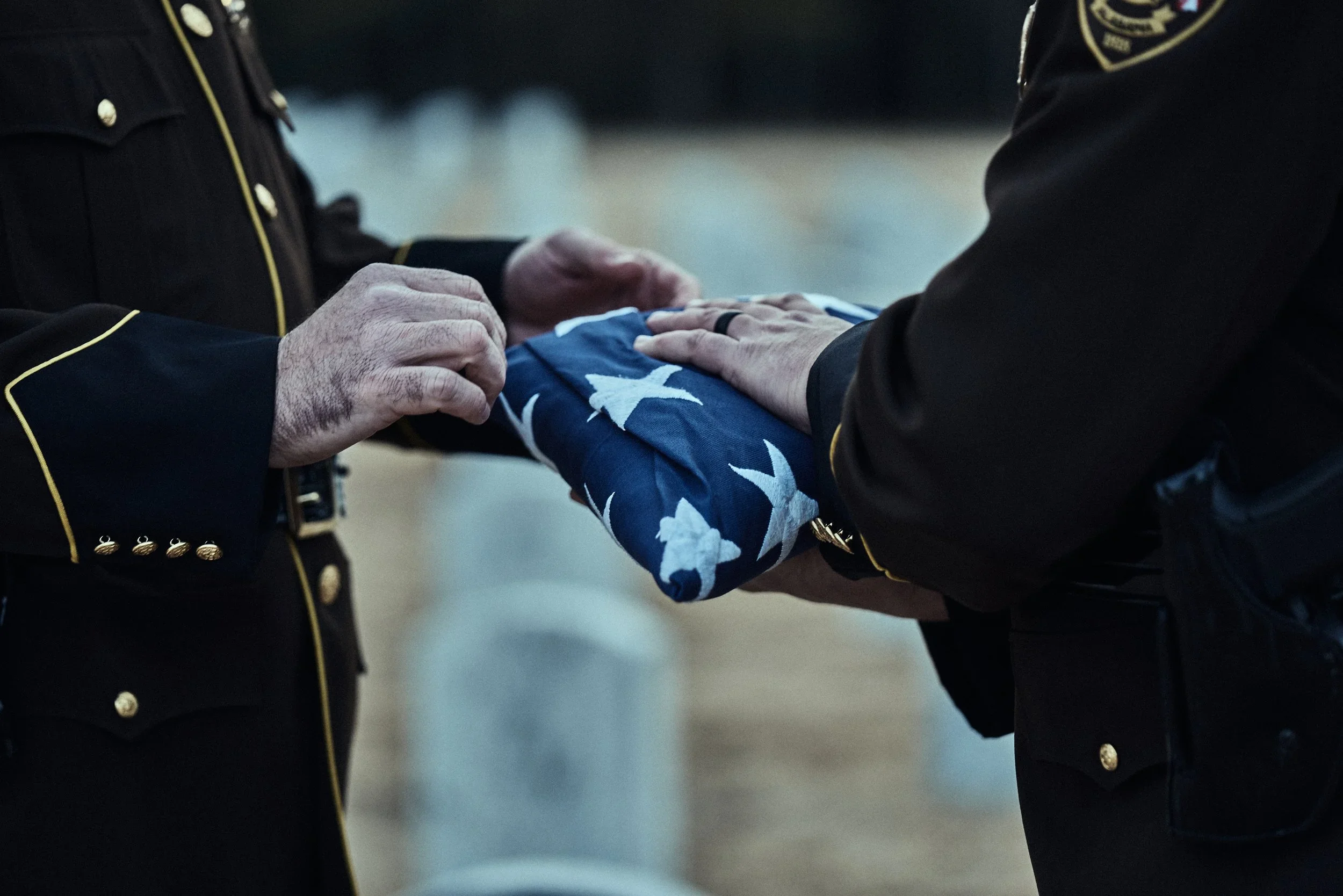 Two uniformed Shelby County Sheriff’s Office deputies fold an American flag during a ceremony.