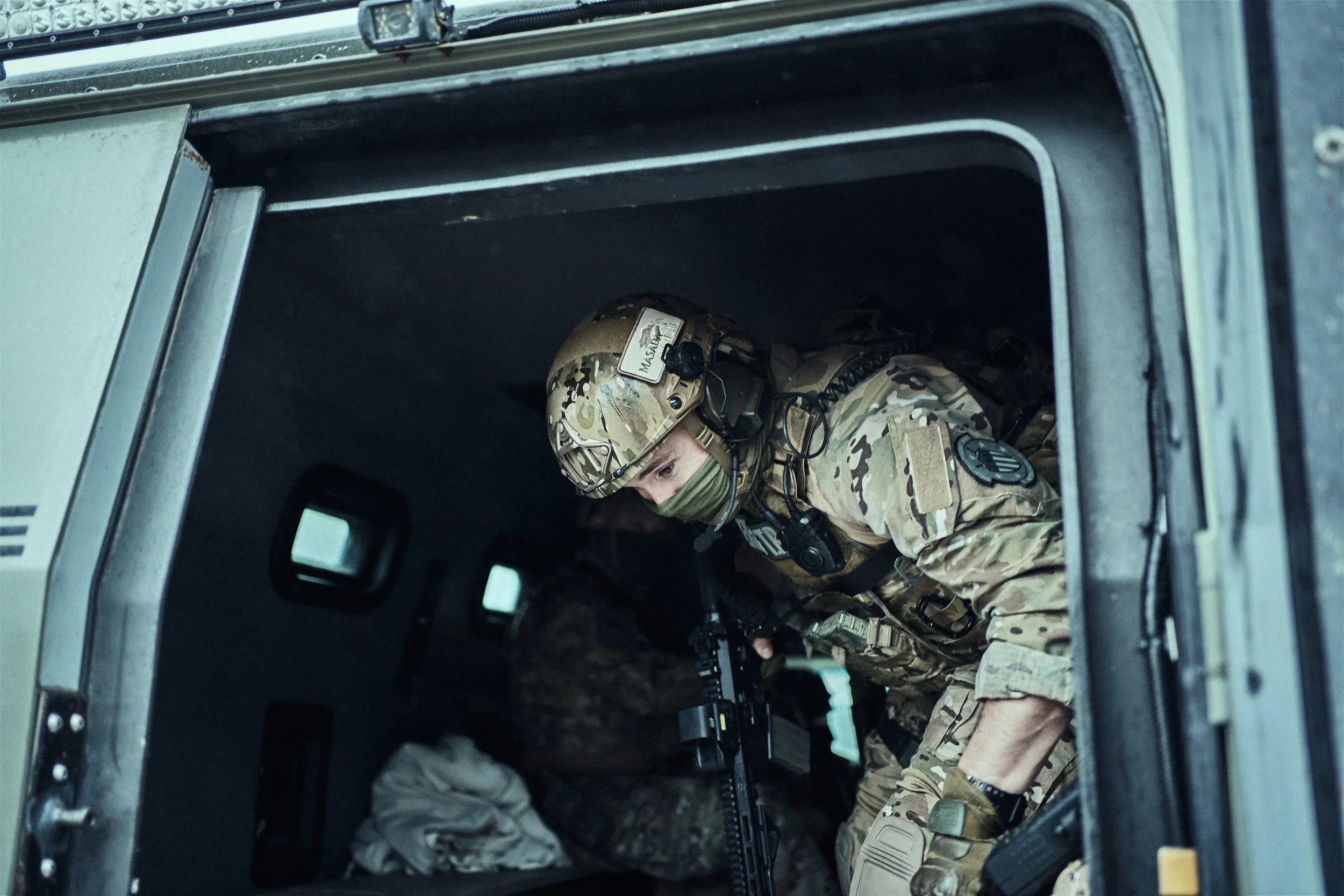 A Shelby County Sheriff’s Office tactical deputy wearing a helmet and headset looks out from an armored vehicle.