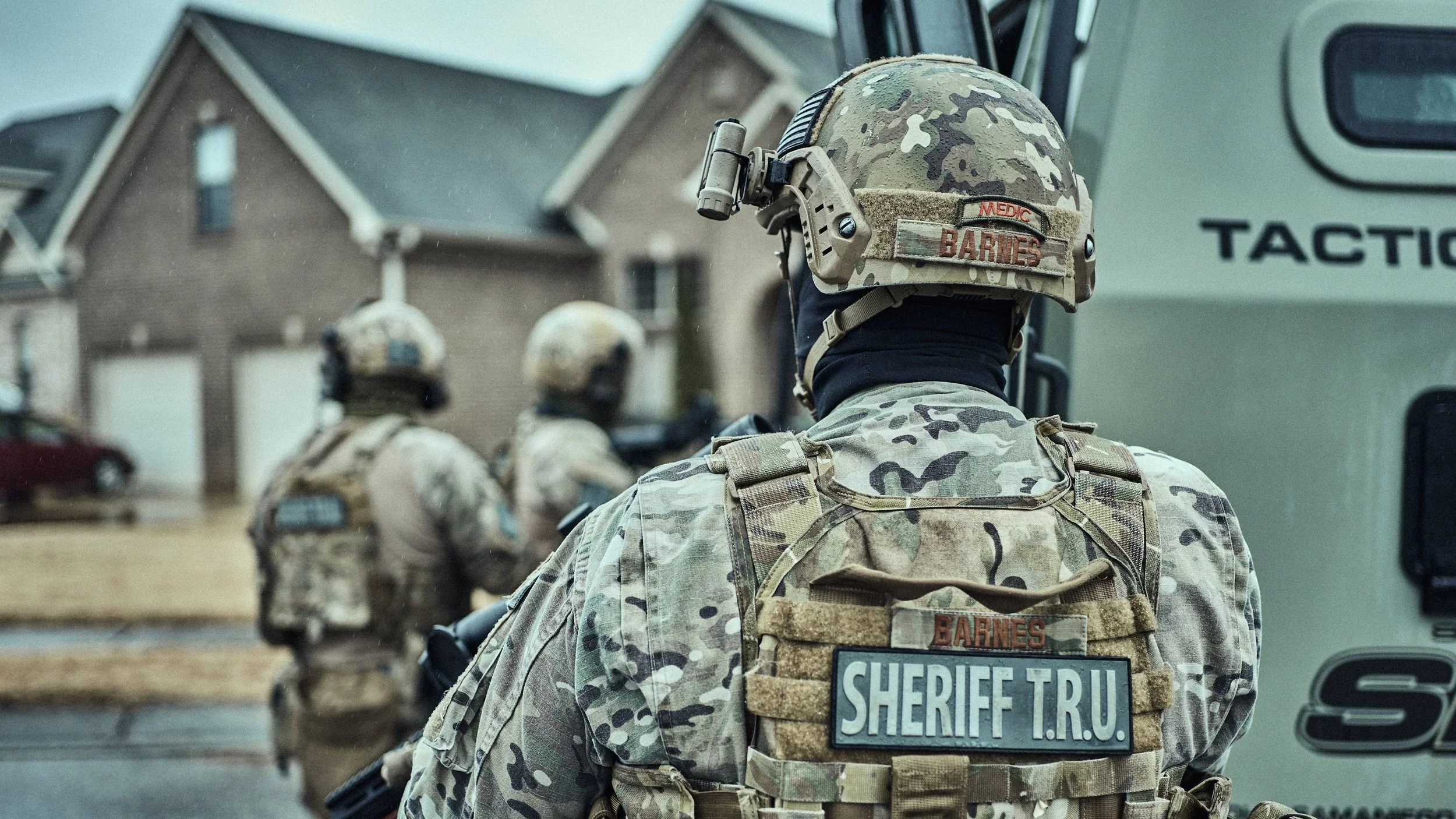 Shelby County Sheriff’s Office tactical deputies stand beside an armored tactical vehicle in a residential neighborhood.