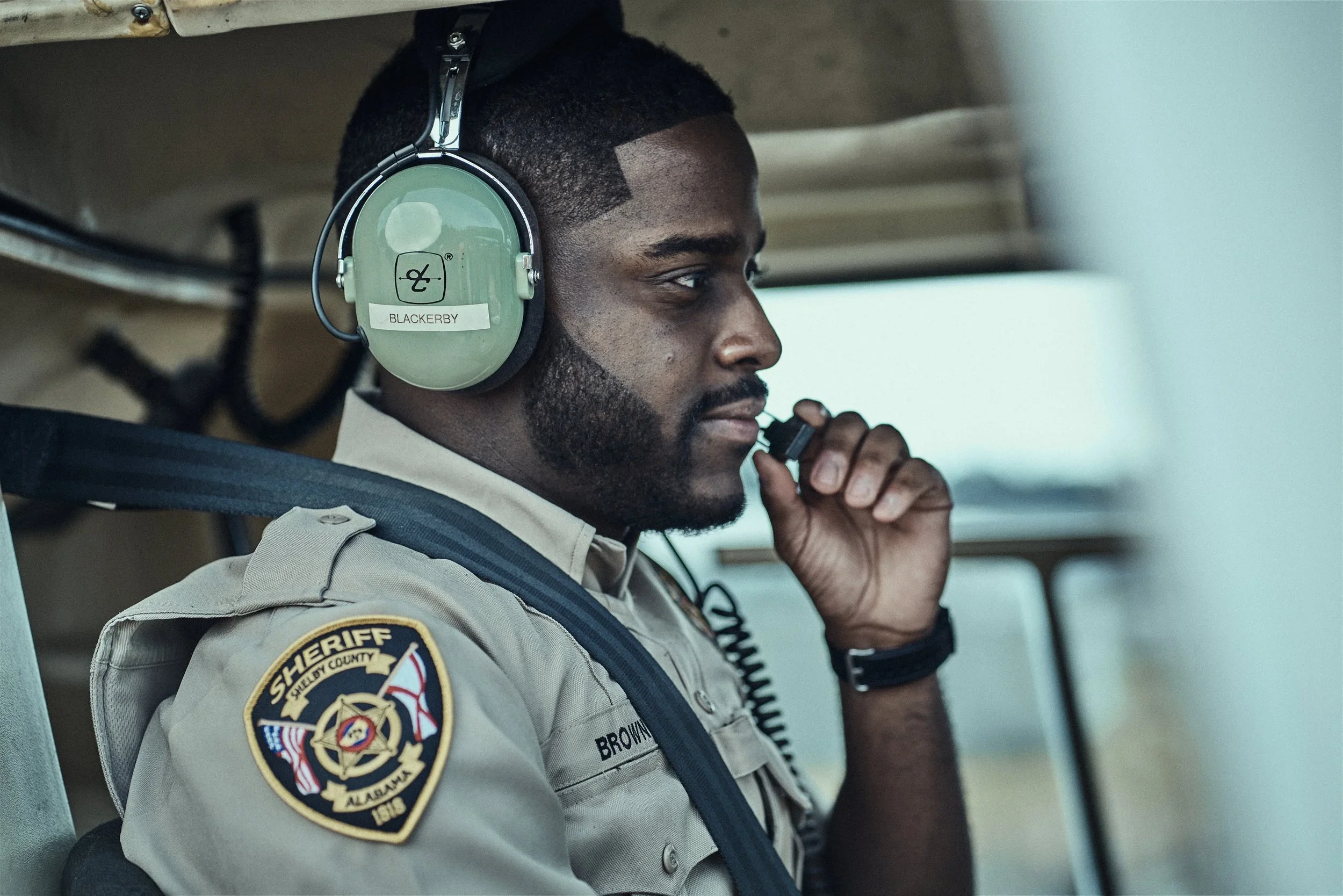 A Shelby County Sheriff’s Office deputy wearing a headset and microphone while seated inside a vehicle.