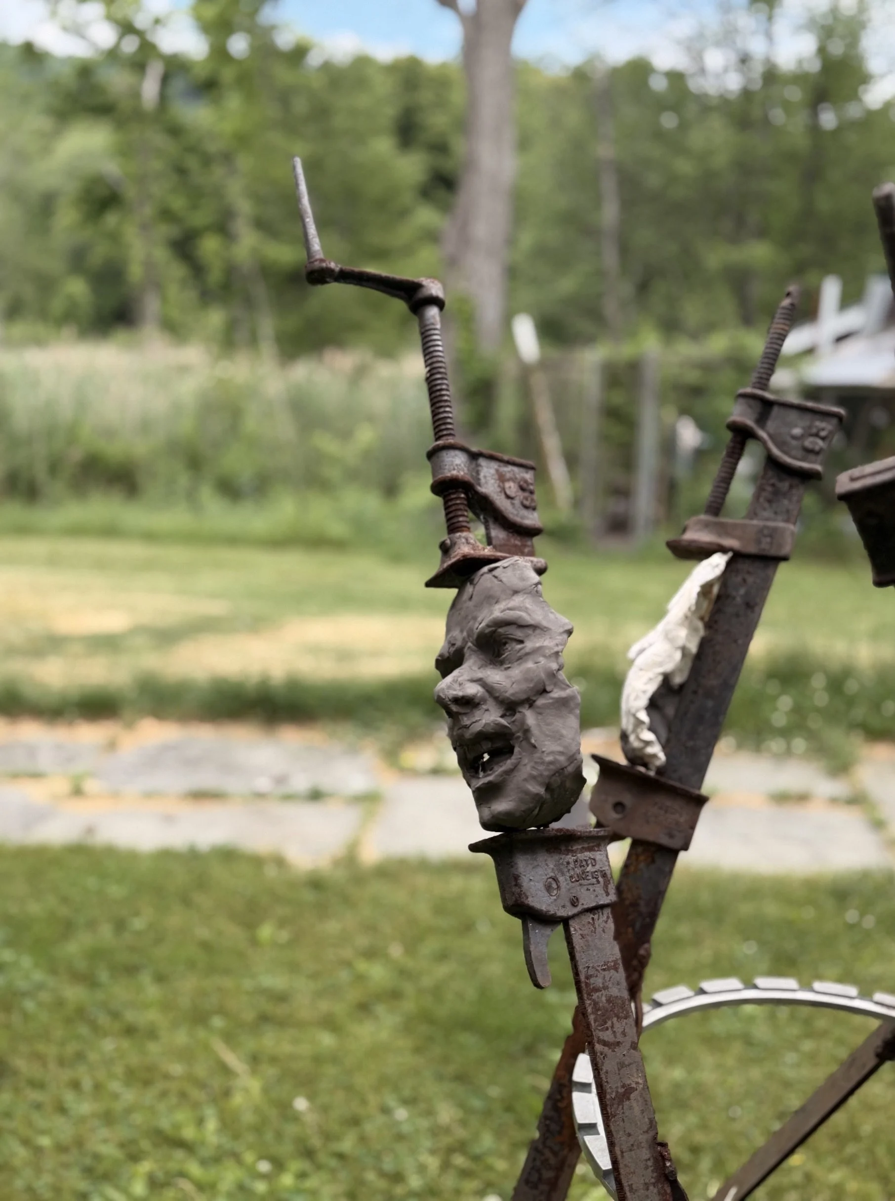 The Tribunal, outdoor sculpture by New York sculptor Aleksandra Scepanovic featuring reclaimed industrial steel and fired clay figures. Clay face detail
