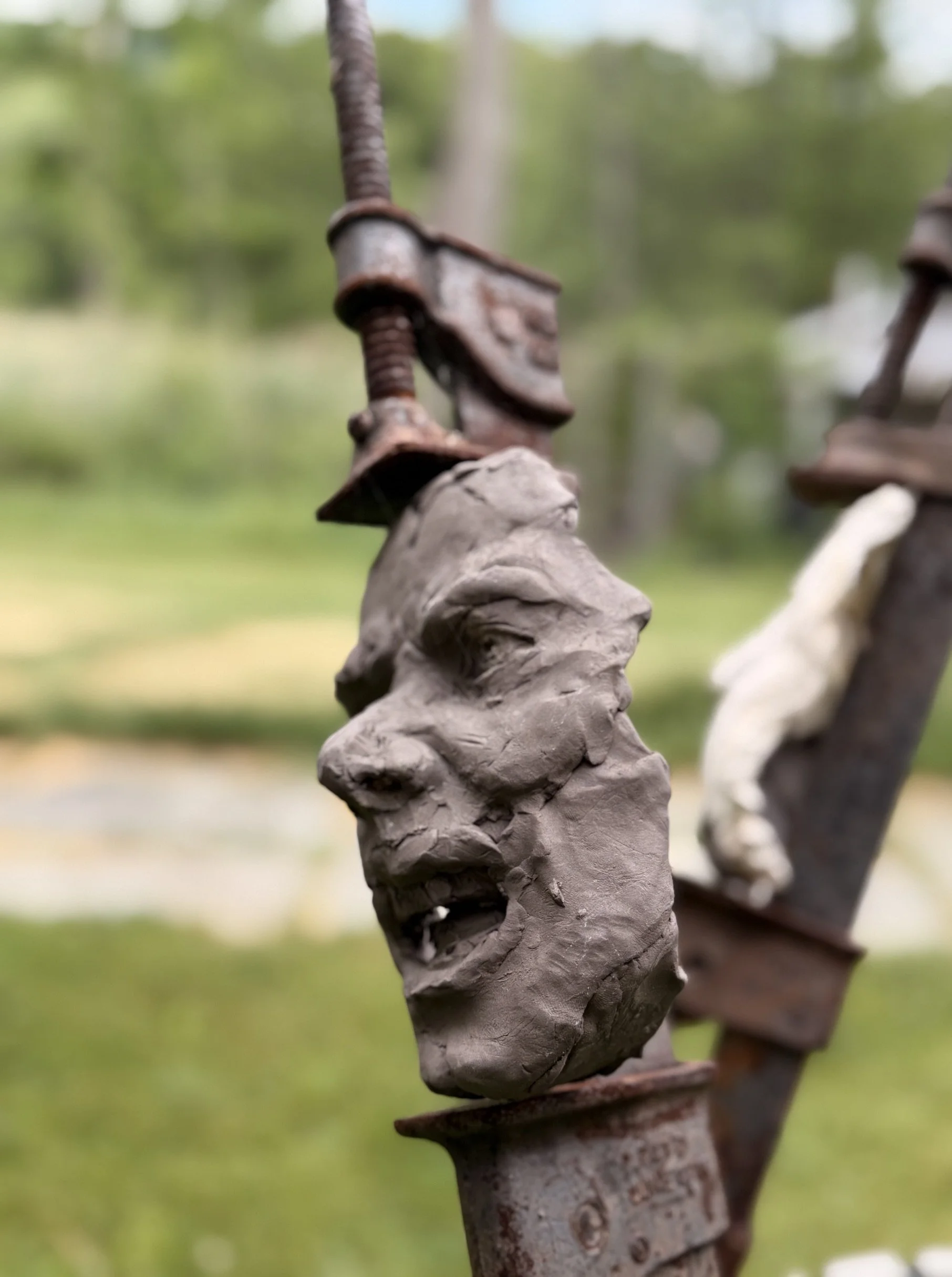 The Tribunal, outdoor sculpture by New York sculptor Aleksandra Scepanovic featuring reclaimed industrial steel and fired clay figures. Dark clay face detail