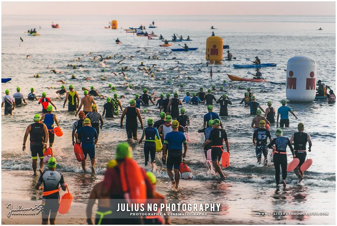 Hundreds of athletes beginning the swim leg during Ironman Desaru Coast, showcasing professional sports event photography.