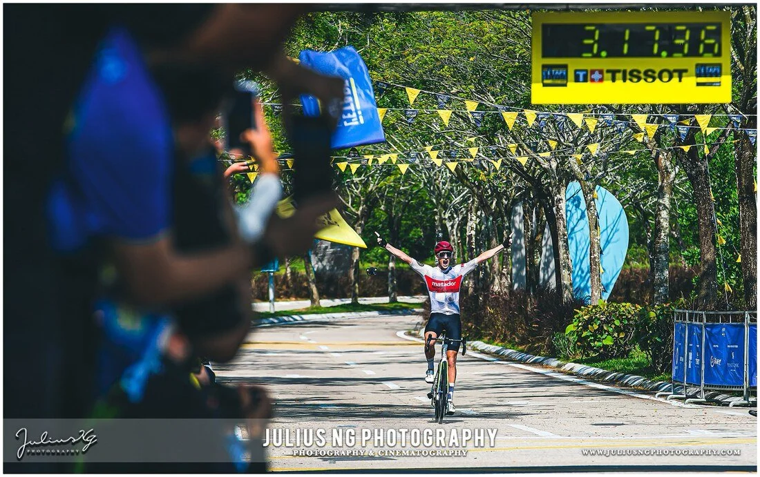 Cyclist celebrating victory at the finish line during L'Étape Malaysia by Tour de France, photographed by Julius Ng Photography.