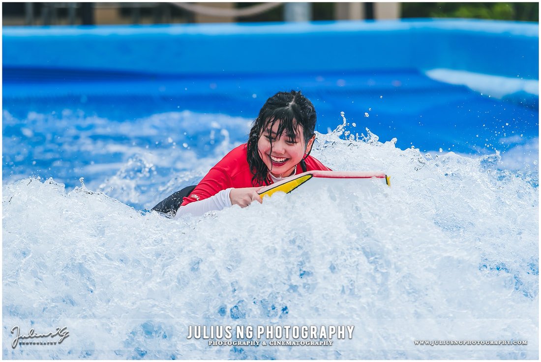 Coca-Cola employees enjoying the FlowRider surfing attraction during a corporate family day and team building event at Adventure Waterpark Desaru Coast, photographed by Julius Ng Photography.
