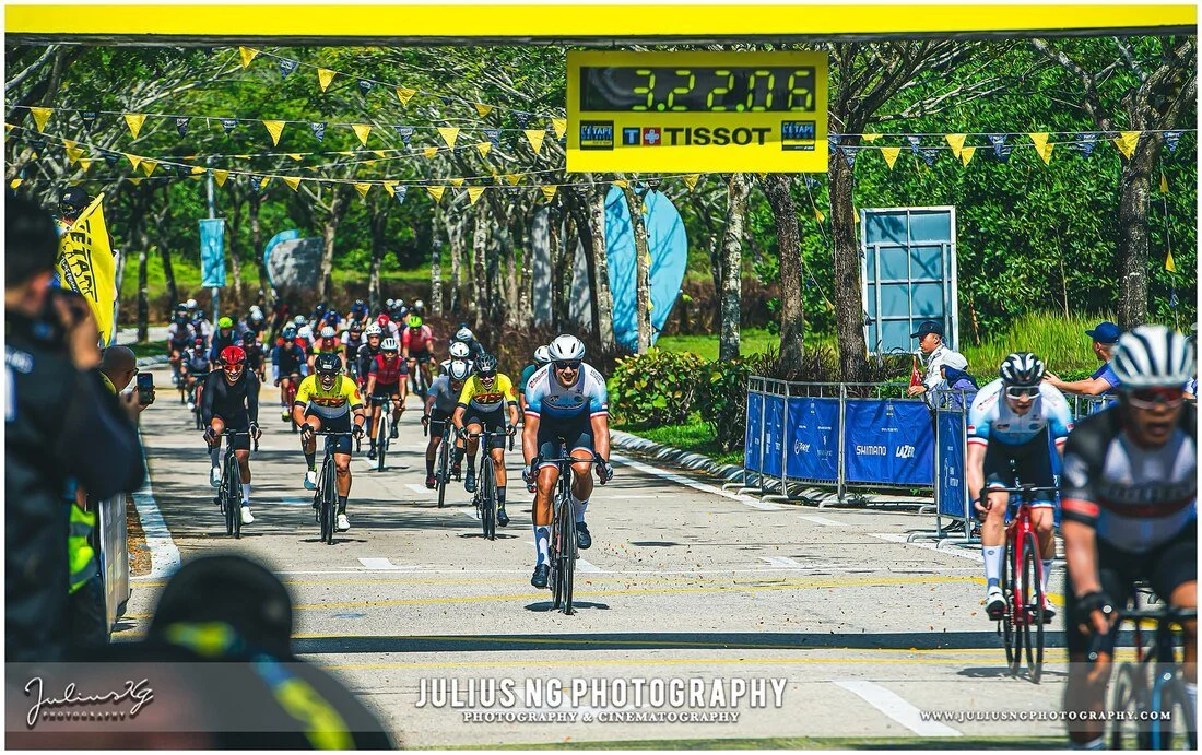 Professional cycling race finish at L'Étape Malaysia by Tour de France featuring competitive riders crossing the finish line.