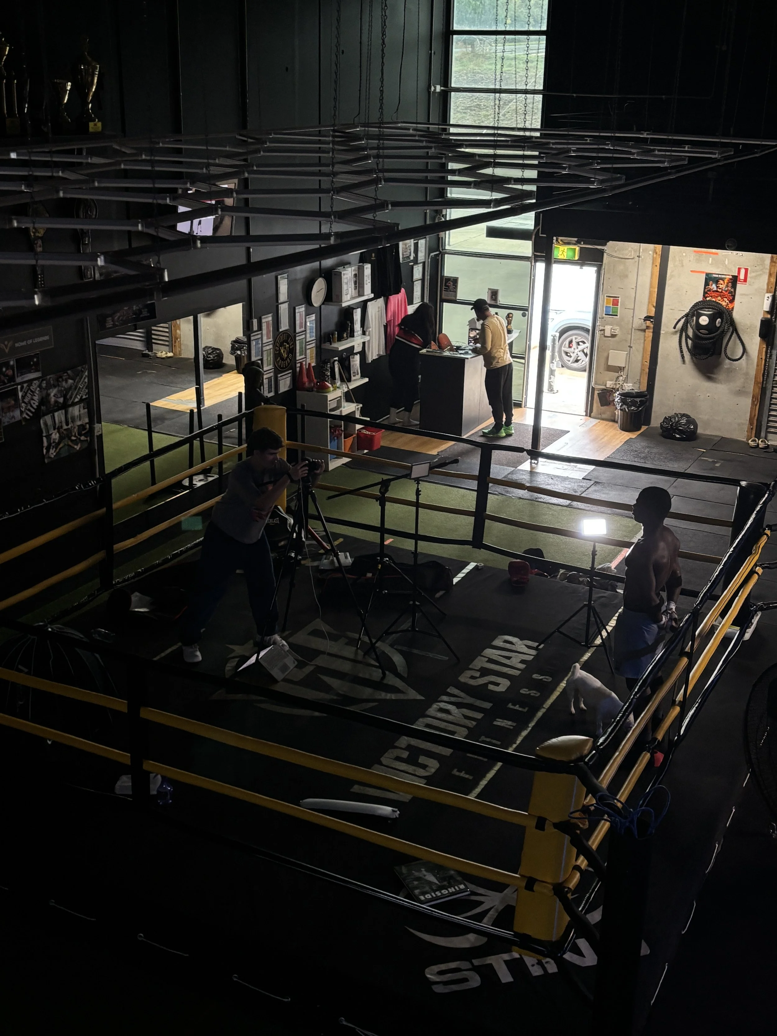 People training in a boxing gym with a boxing ring, punching bags, and workout equipment.