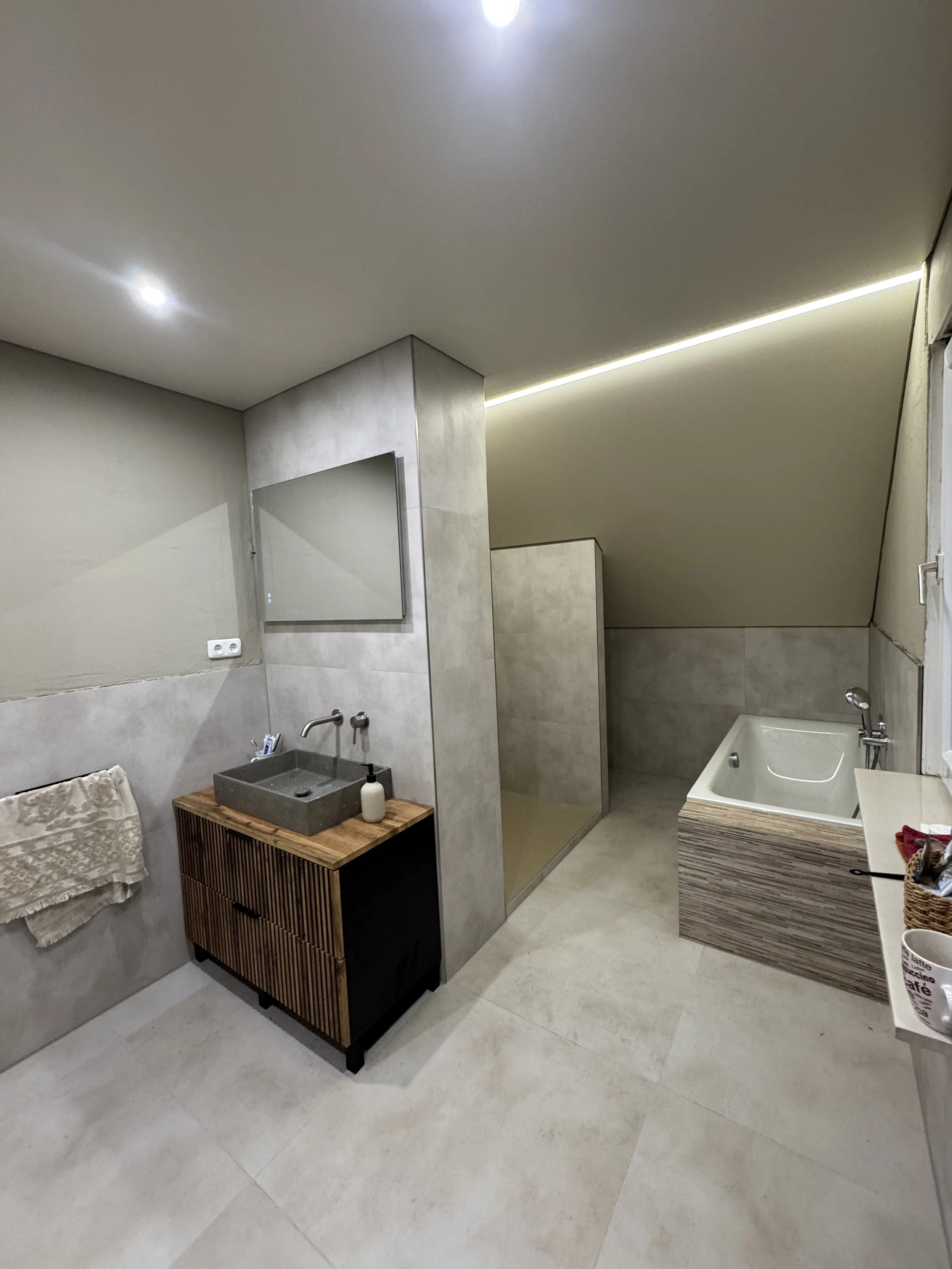 Modernes Badezimmer mit Dusche, Waschbecken, Spiegel, Handtuch und Badezubehör in neutralen Tönen.